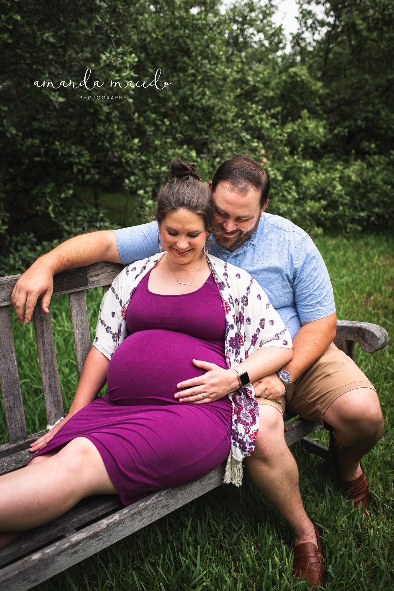 Maternity photographer, couple sitting on bench looking at baby bumb