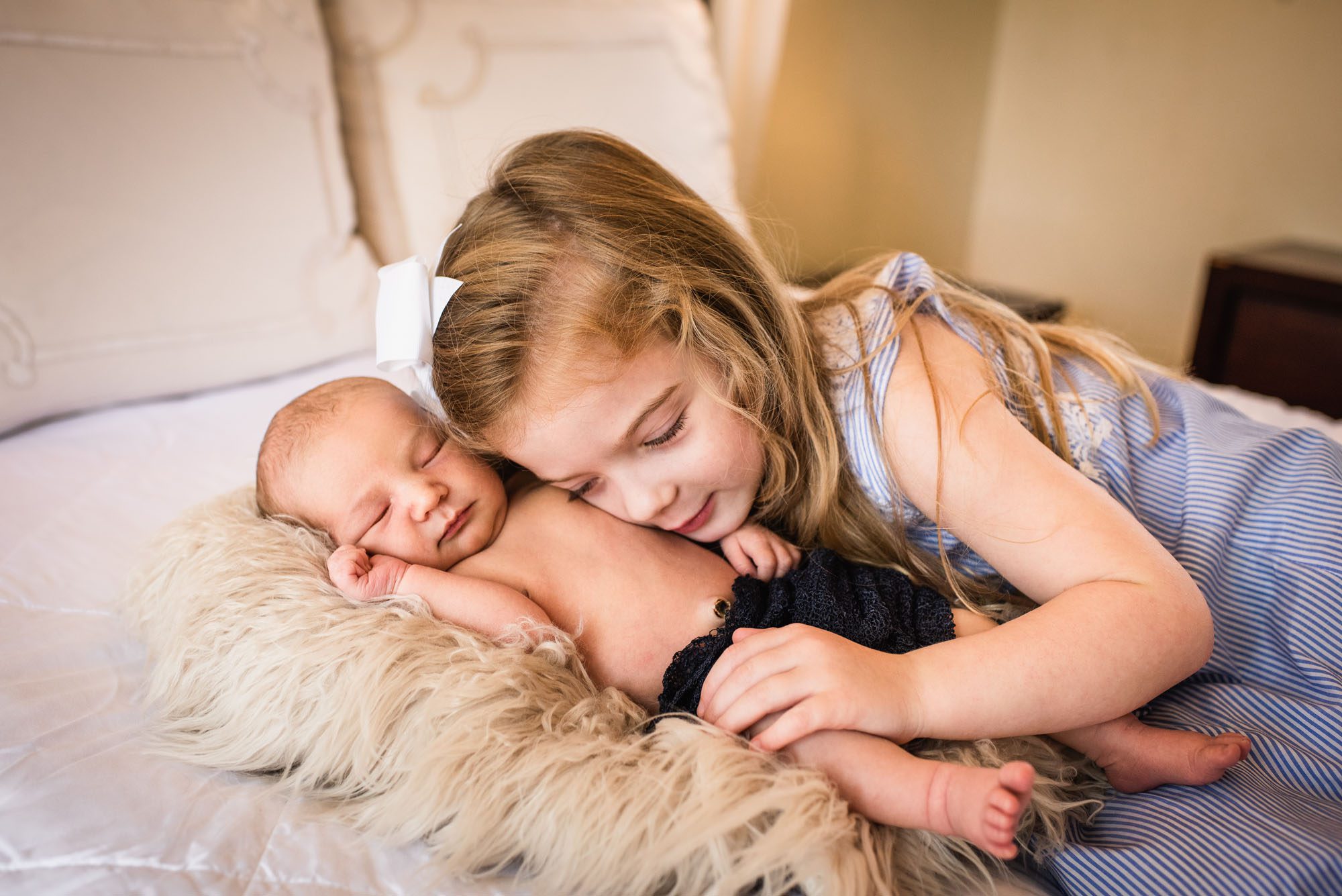 Newborn photographer, sister cuddling newborn baby brother