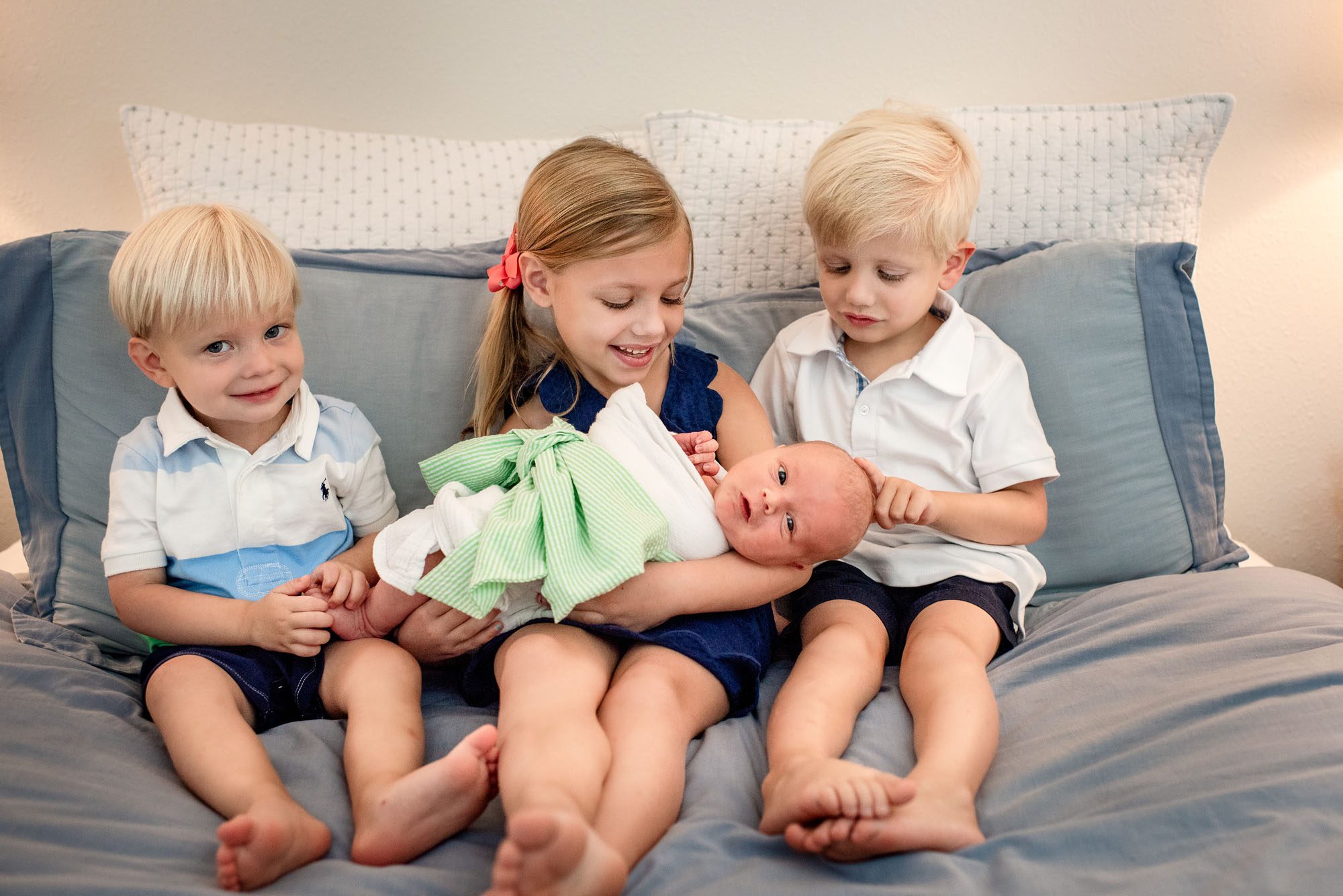 San Antonio newborn photographer, siblings on bed with newborn baby