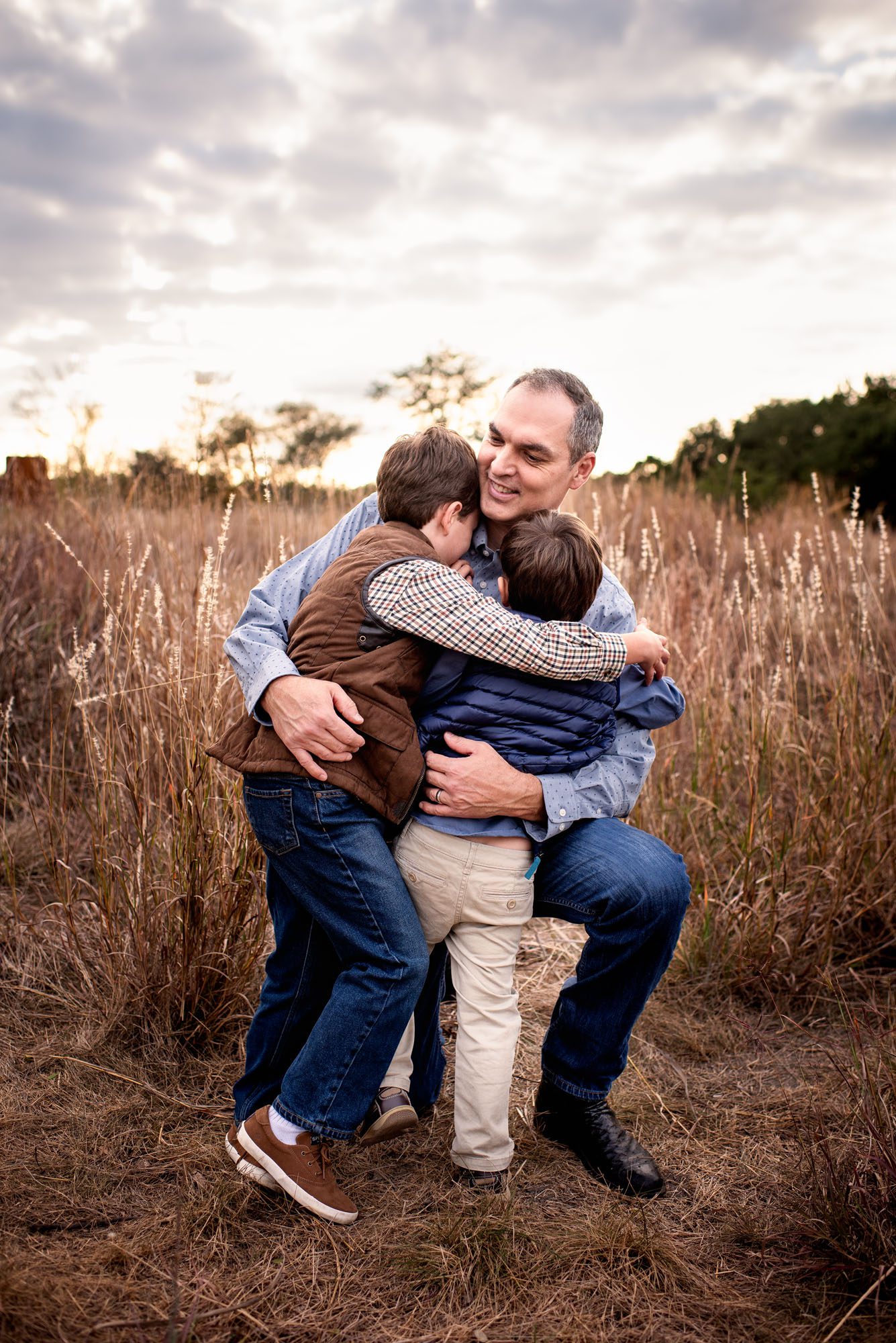 Boys hugging Dad in a grassy field, San Antonio Family Photographer