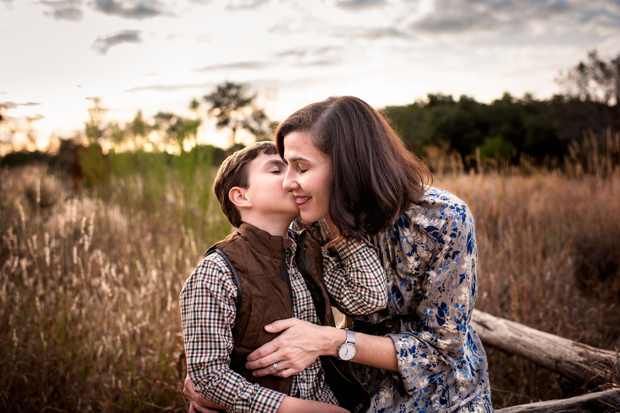 Son kissing Mom on the cheek in a grassy field, San Antonio Family Photographer