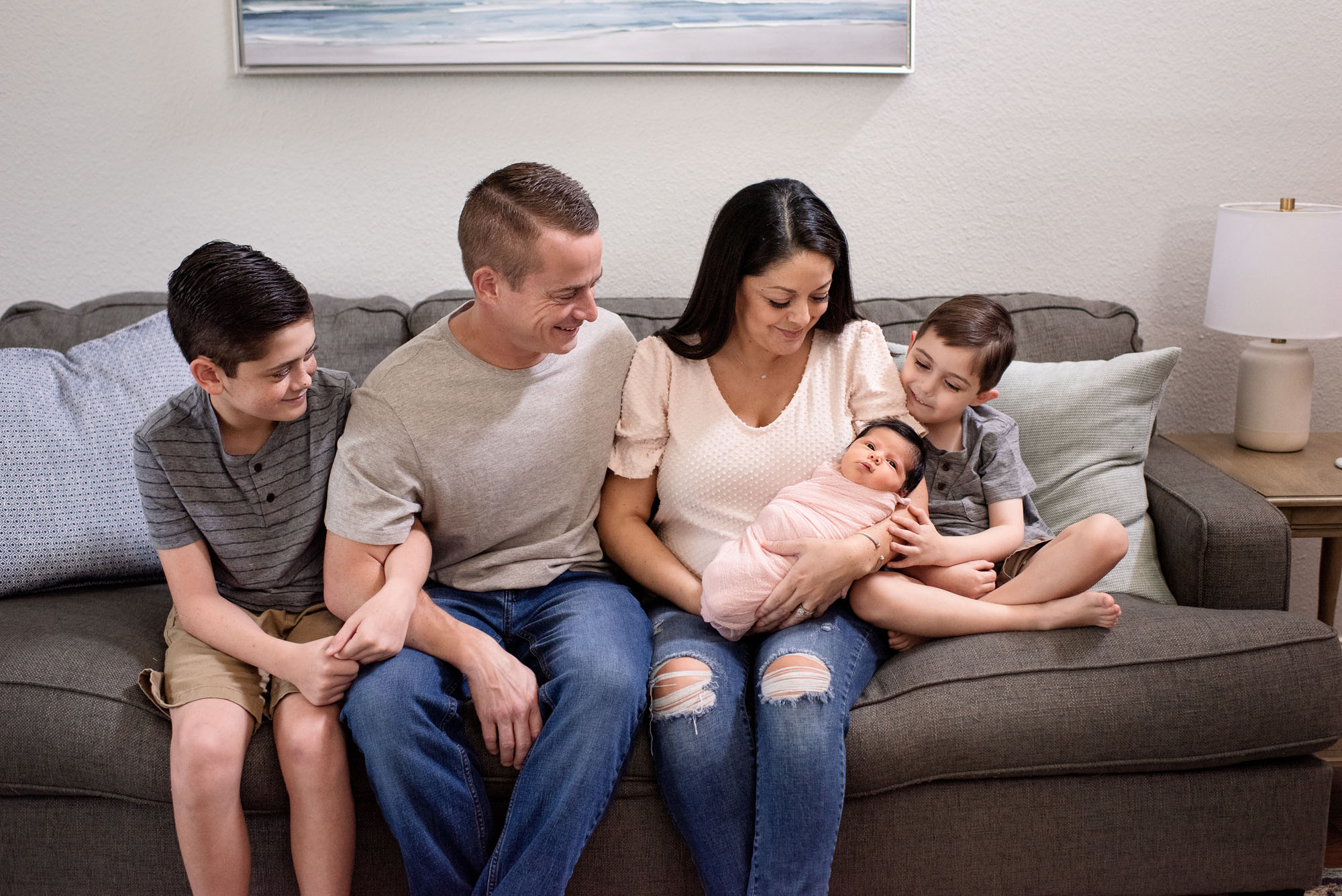 Family sitting on couch holding newborn, San Antonio Newborn photographer