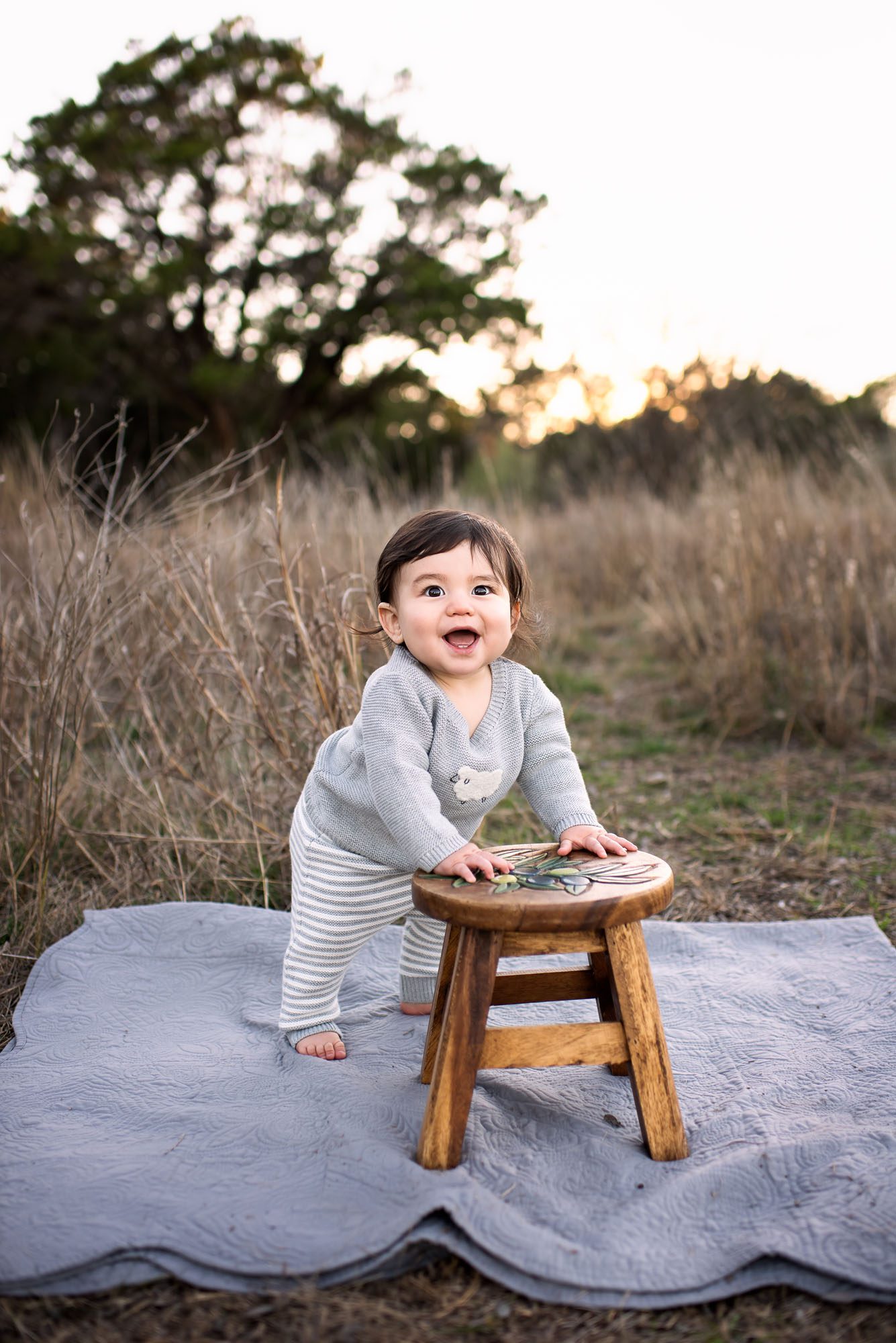 Baby smiling standing by stool in field at sunset, San Antonio baby photographer