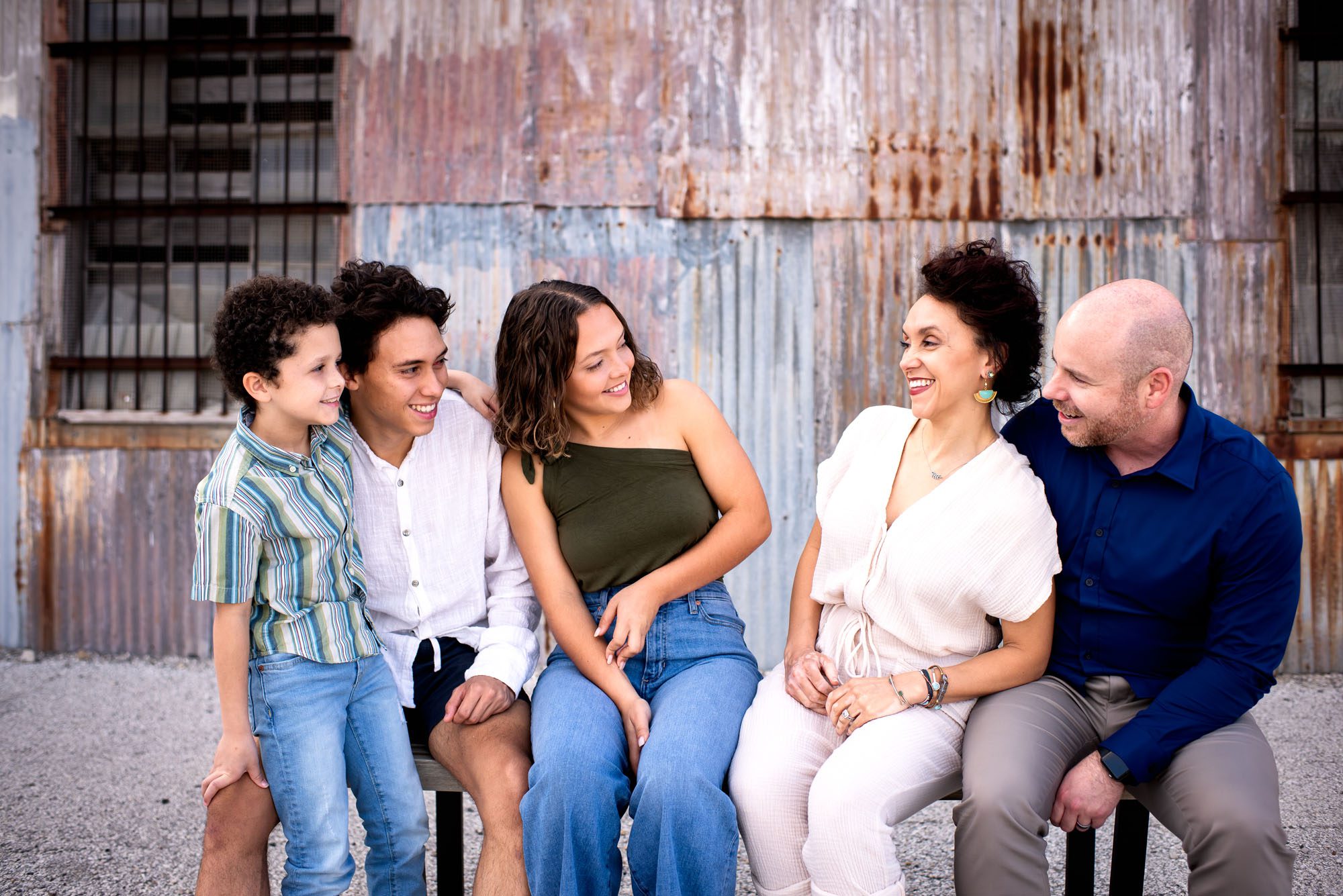 Family sitting on bench in front of urban building, San Antonio lifestyle photographer