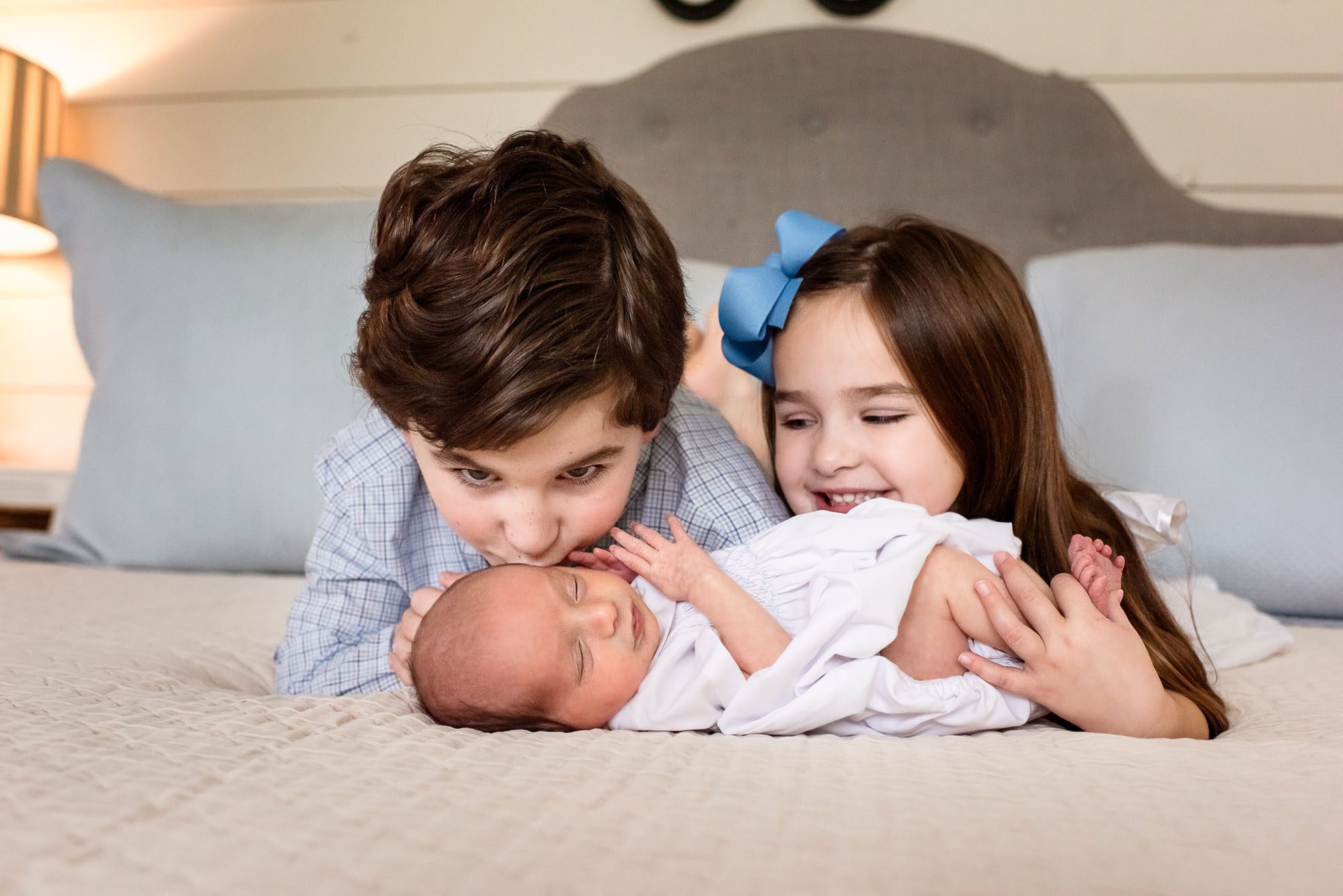 Siblings laying with newborn baby on bed, Lifestyle newborn photography San Antonio