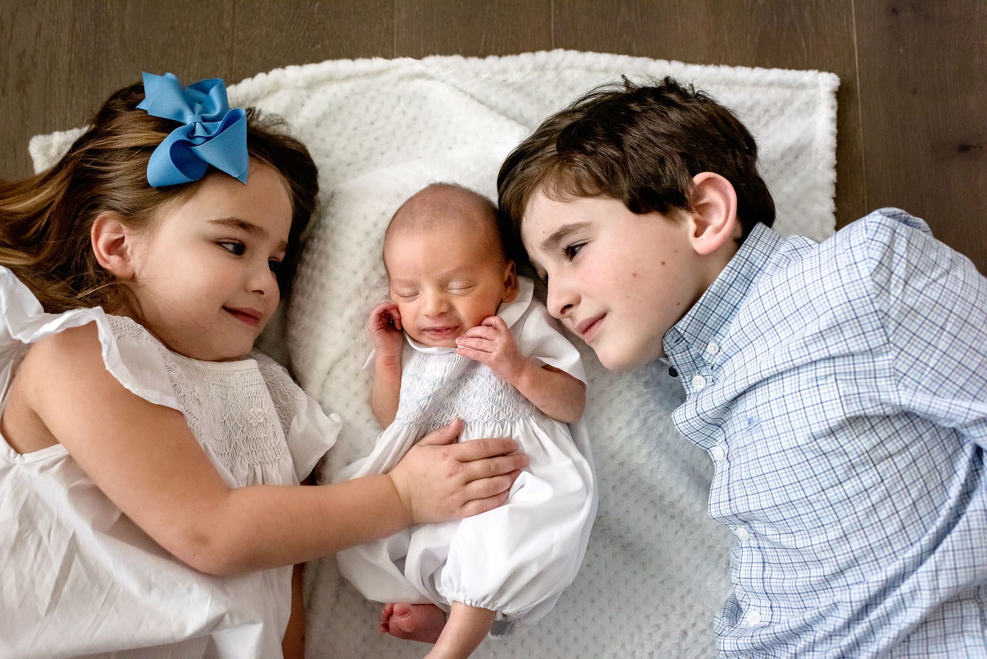 Siblings laying with newborn baby on blanket, Lifestyle newborn photography San Antonio
