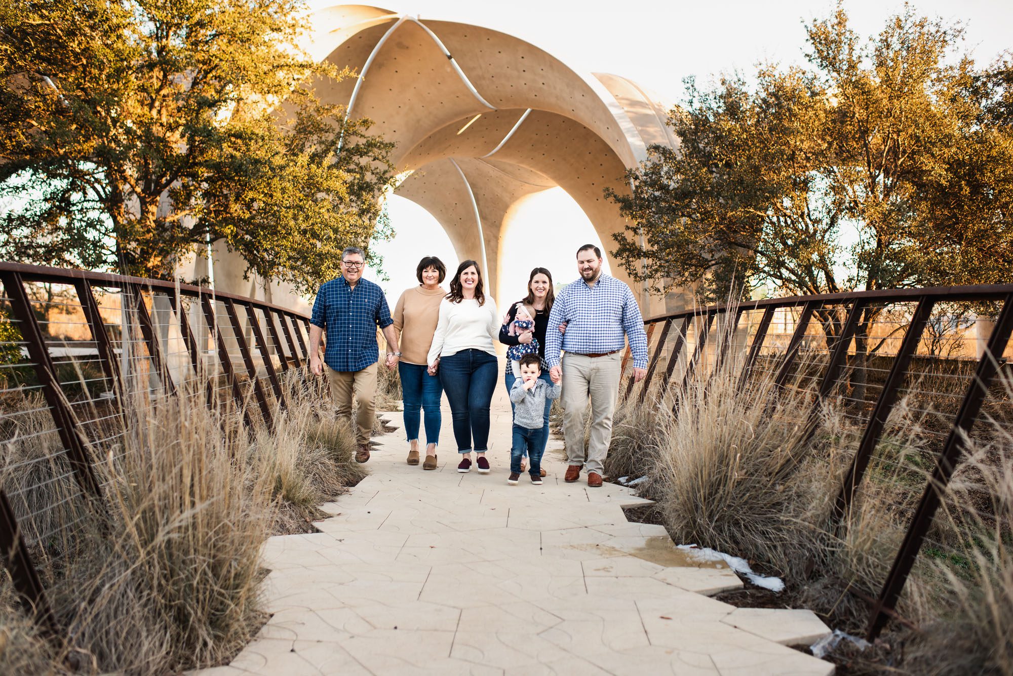 Family walking on bridge with archway behind them, Lifestyle Photographer San Antonio