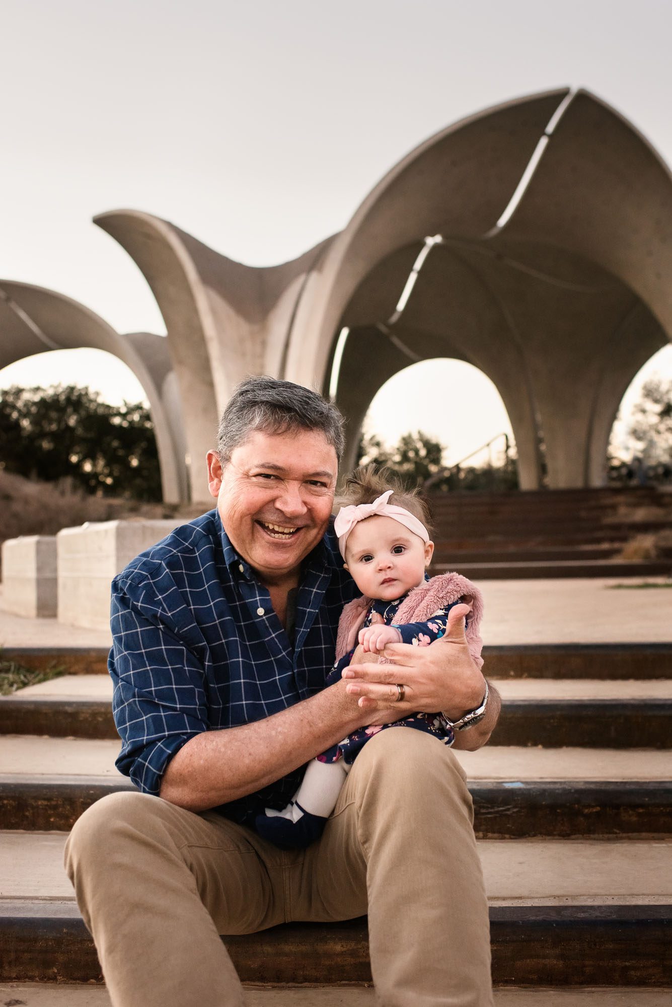 Gradfather sitting with granddaughter in front of sculptural arch, San Antonio Family Photographer