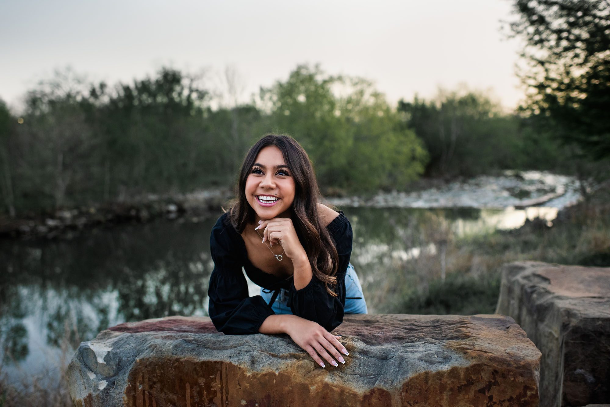 Girl smiling and sitting by the San Antonio River, Best Senior Photographer in San Antonio