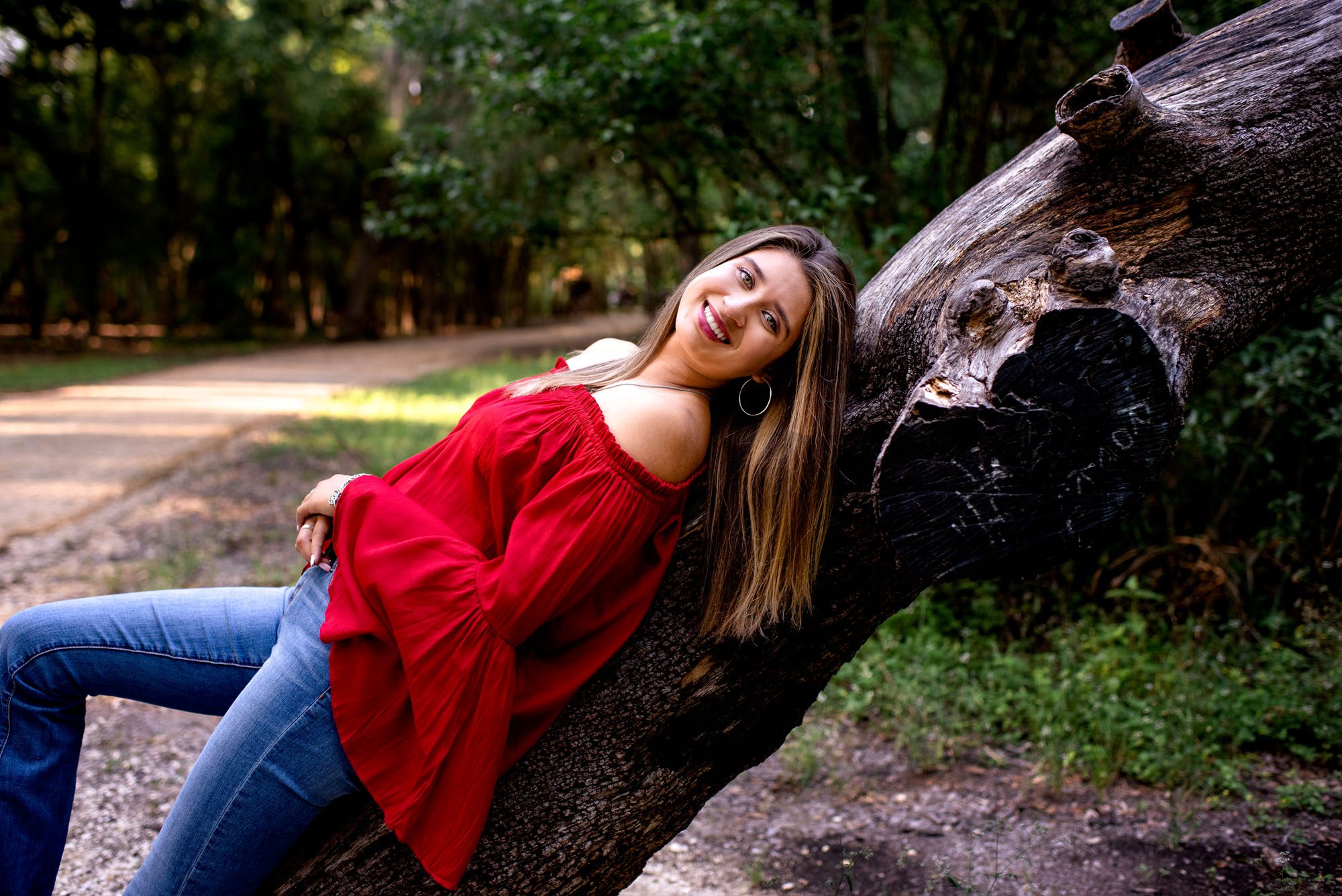 Girl in flowy red shirt leaning on a tree in the woods, San Antonio Senior Photographer
