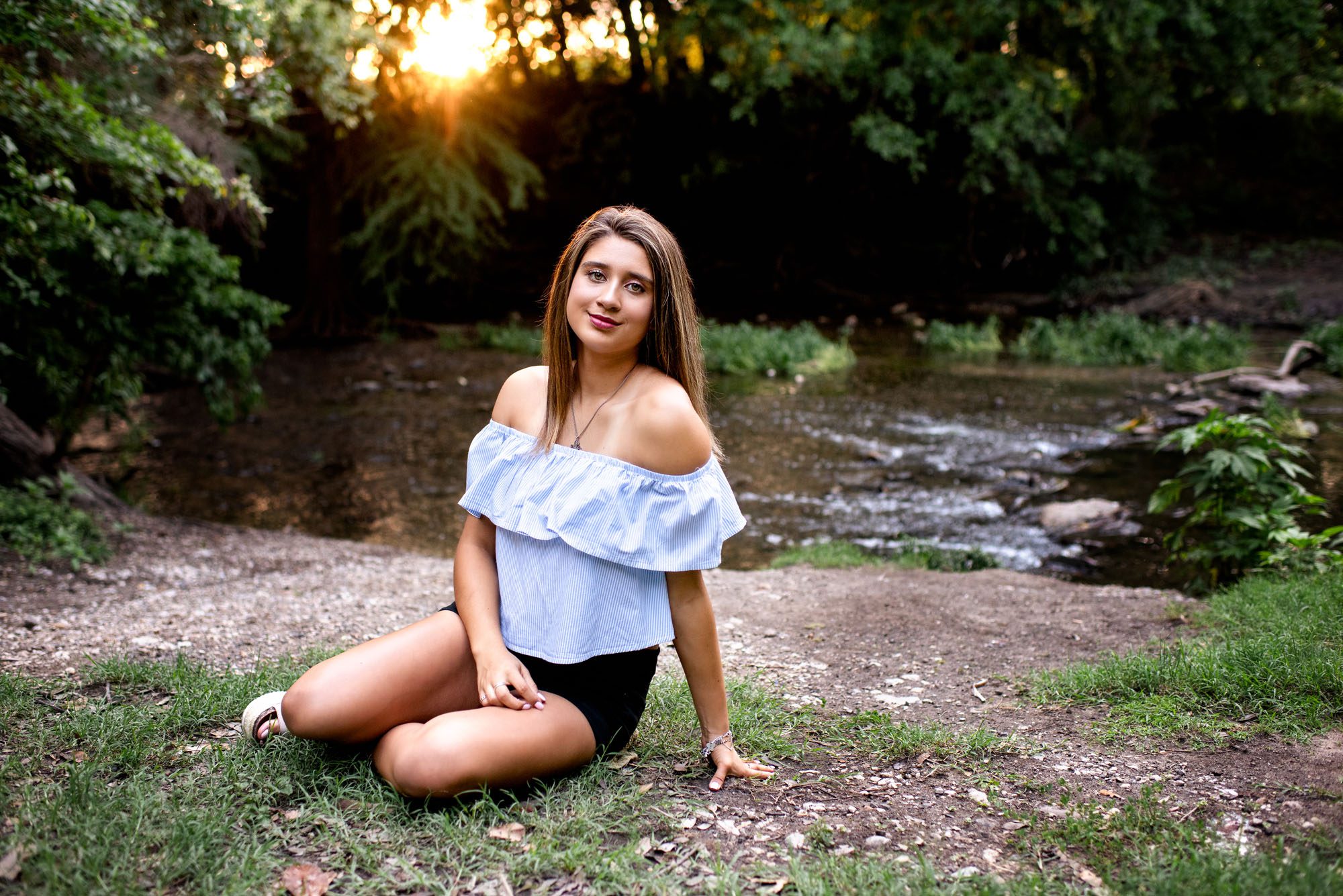 Senior girl sitting by creek with golden sunset, San Antonio Senior Photographer
