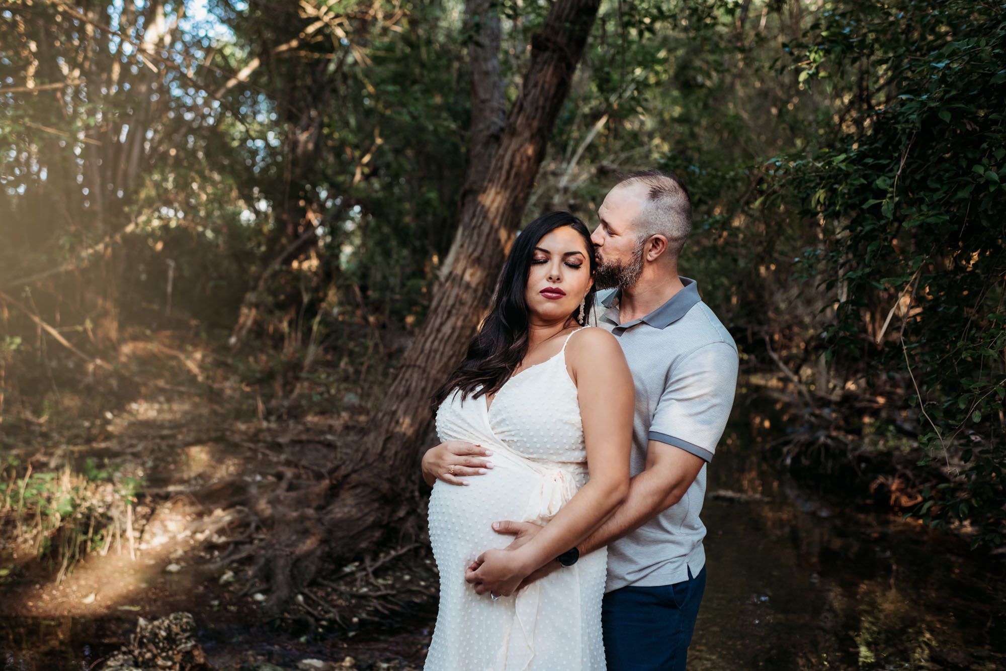 Pregnant woman with husband by creek, San Antonio Maternity Lifestyle Photographer