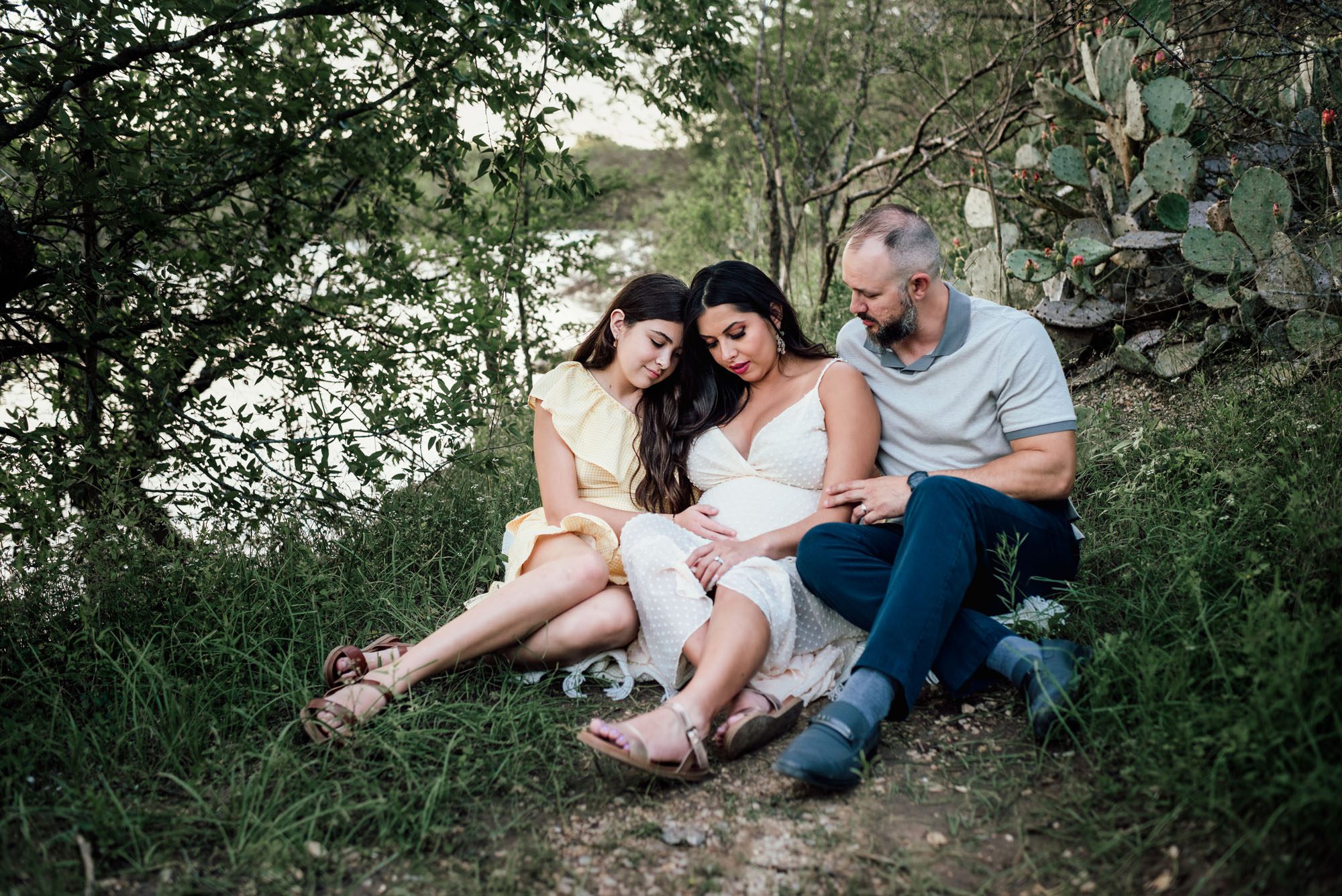Family sitting together looking at pregnant mother's belly, San Antonio Maternity Lifestyle Photographer