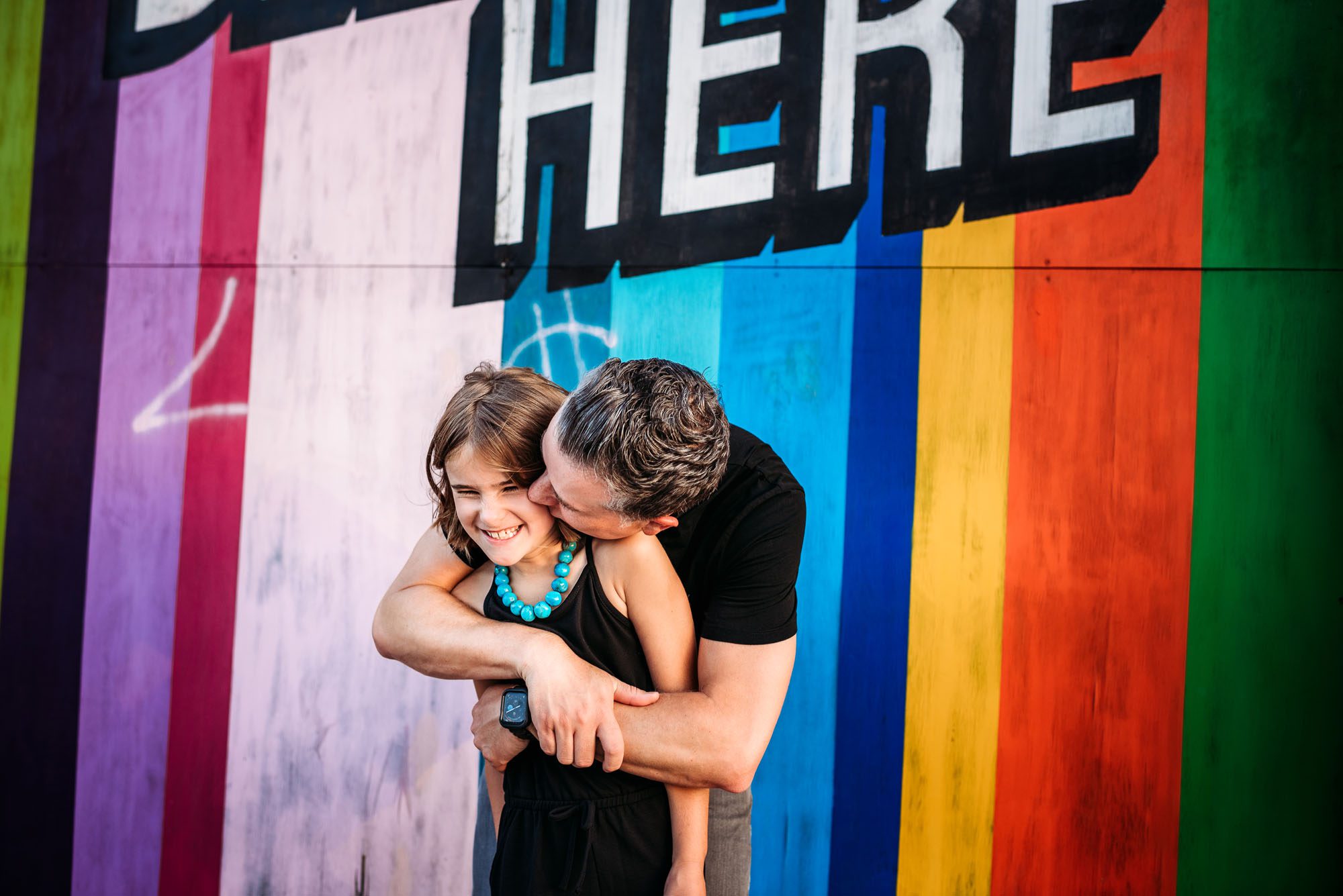 Dad kissing daughter by colorful wall, San Antonio family photographer