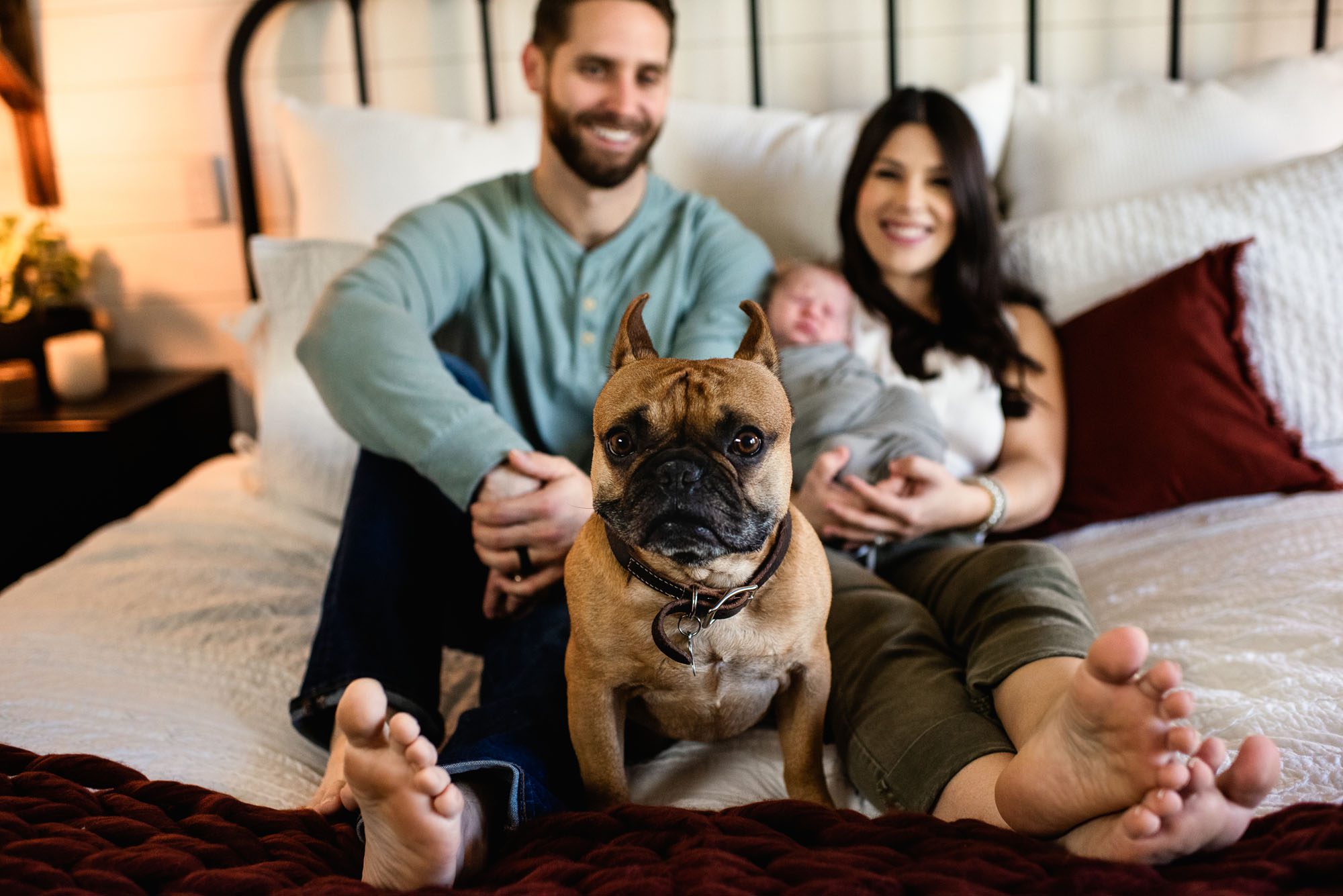San Antonio Newborn Photographer, Couple holding newborn baby on bed with dog