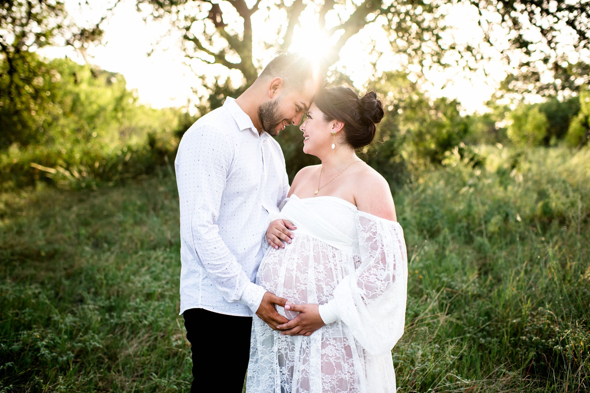 Expectant couple smiling at each other at sunset, San Antonio maternity photographers