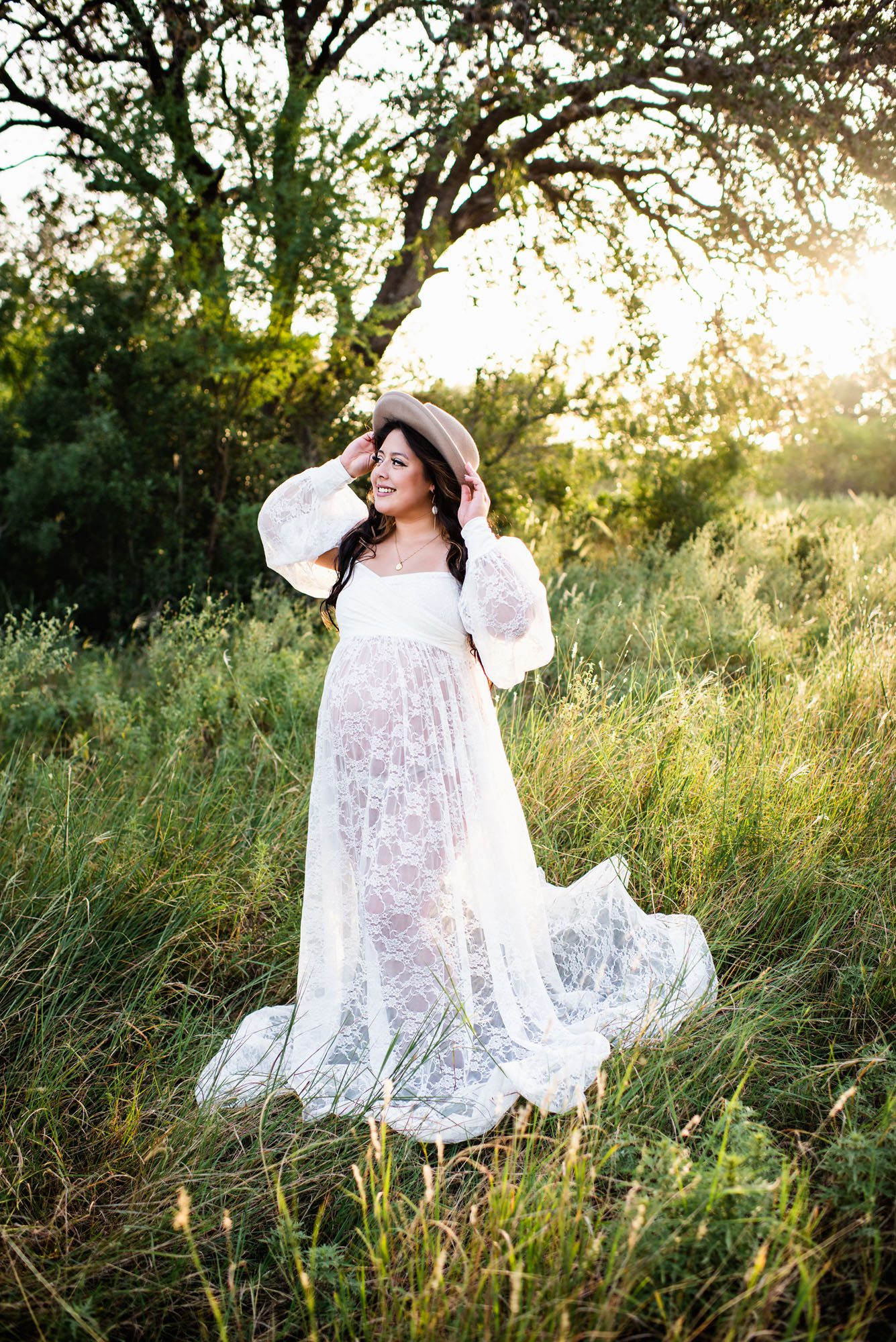 Expectant mother smiling in field in long white lace dress, Best San Antonio maternity photographer