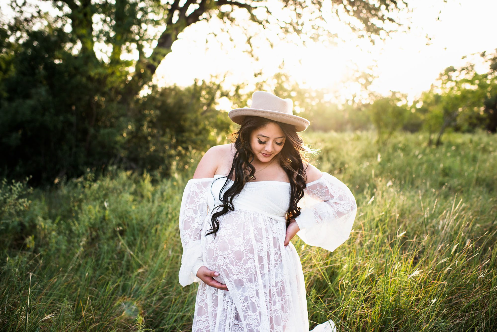 Expectant mother in long white dress and hat, San Antonio maternity session