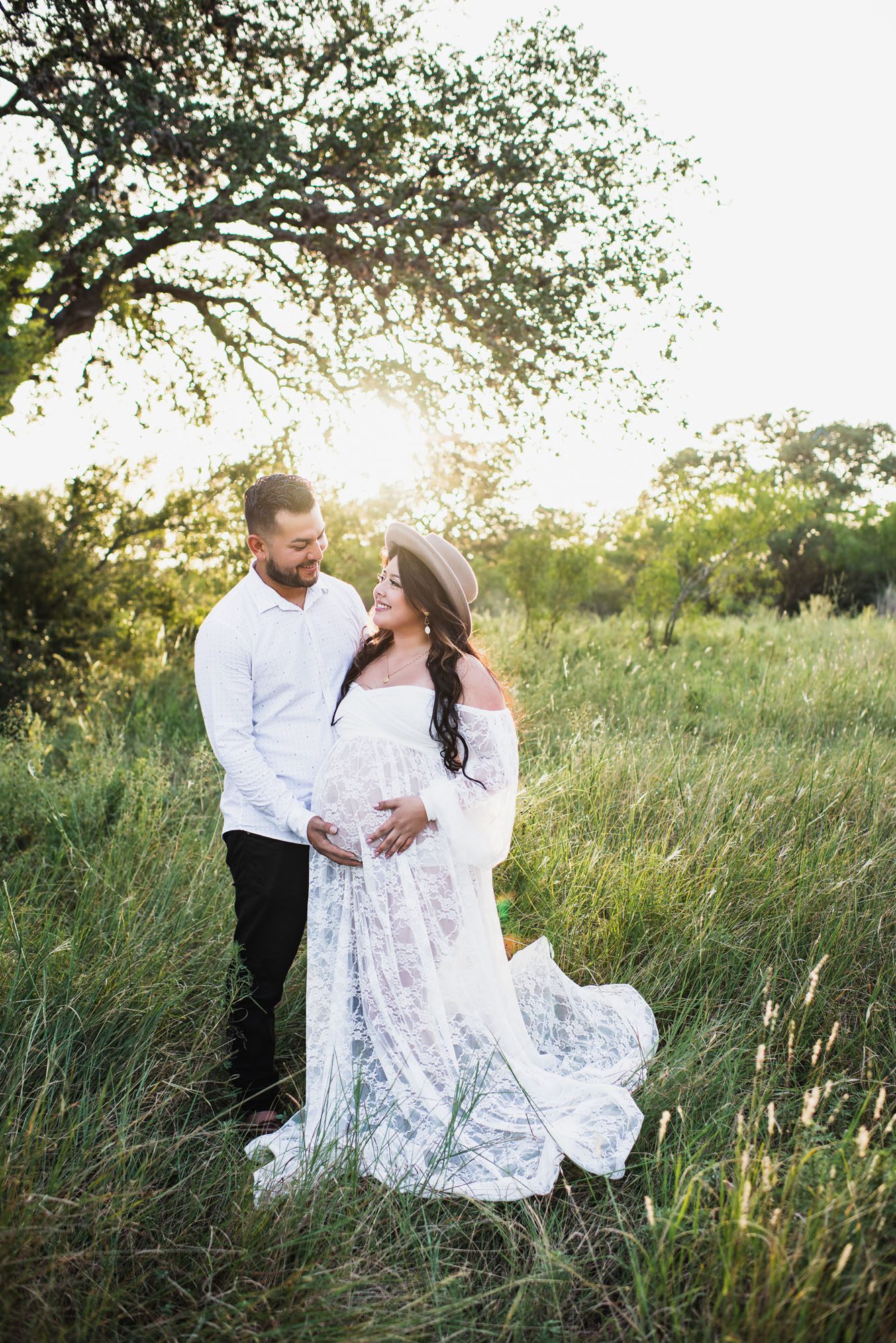 Expectant couple smiling at each other in field, San Antonio maternity lifestyle session