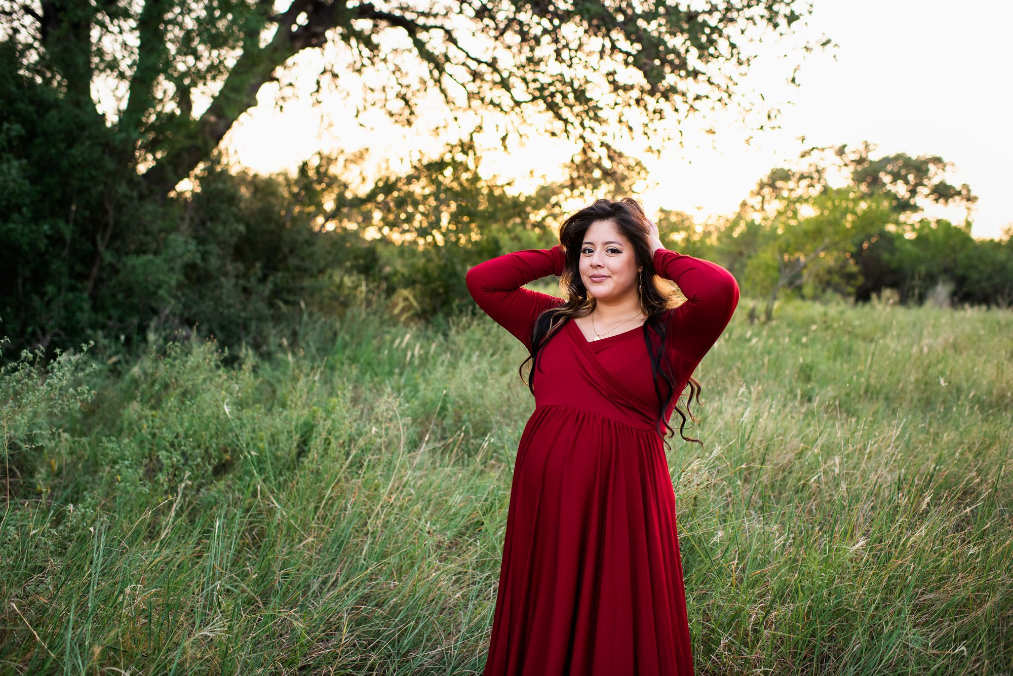 Pregnant mom playing with her hair in a long red dress, San Antonio maternity lifestyle session