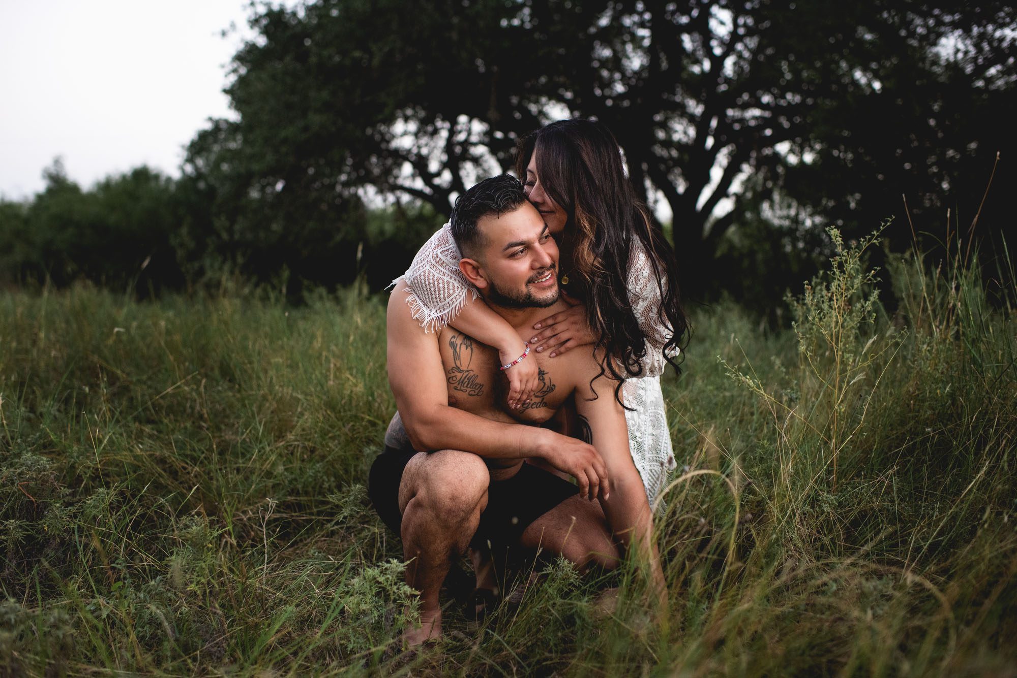 San Antonio Maternity Photographer, Couple snuggling together in a grassy field