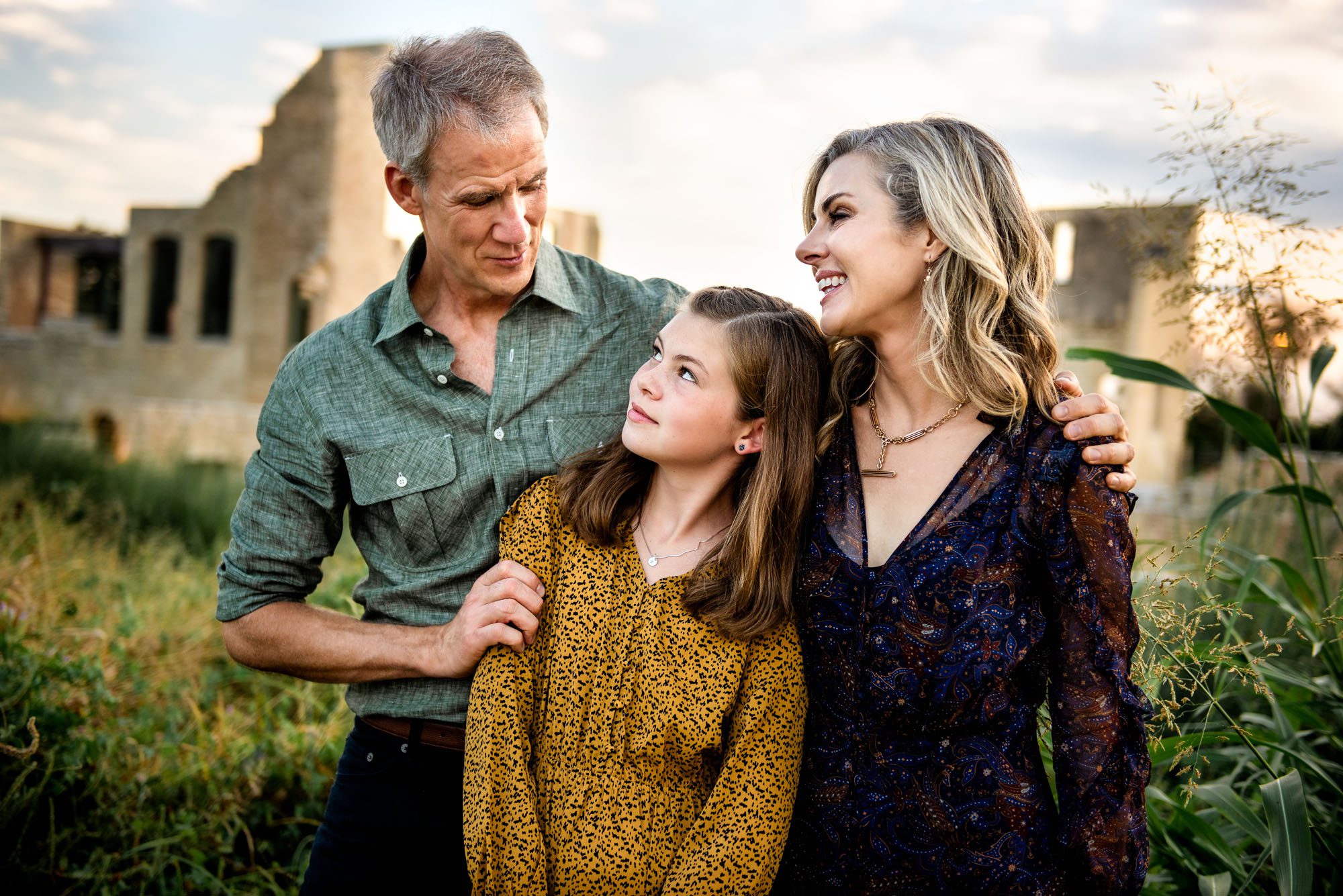 Family smiling at one another in front of old building, Best San Antonio Family Photographer