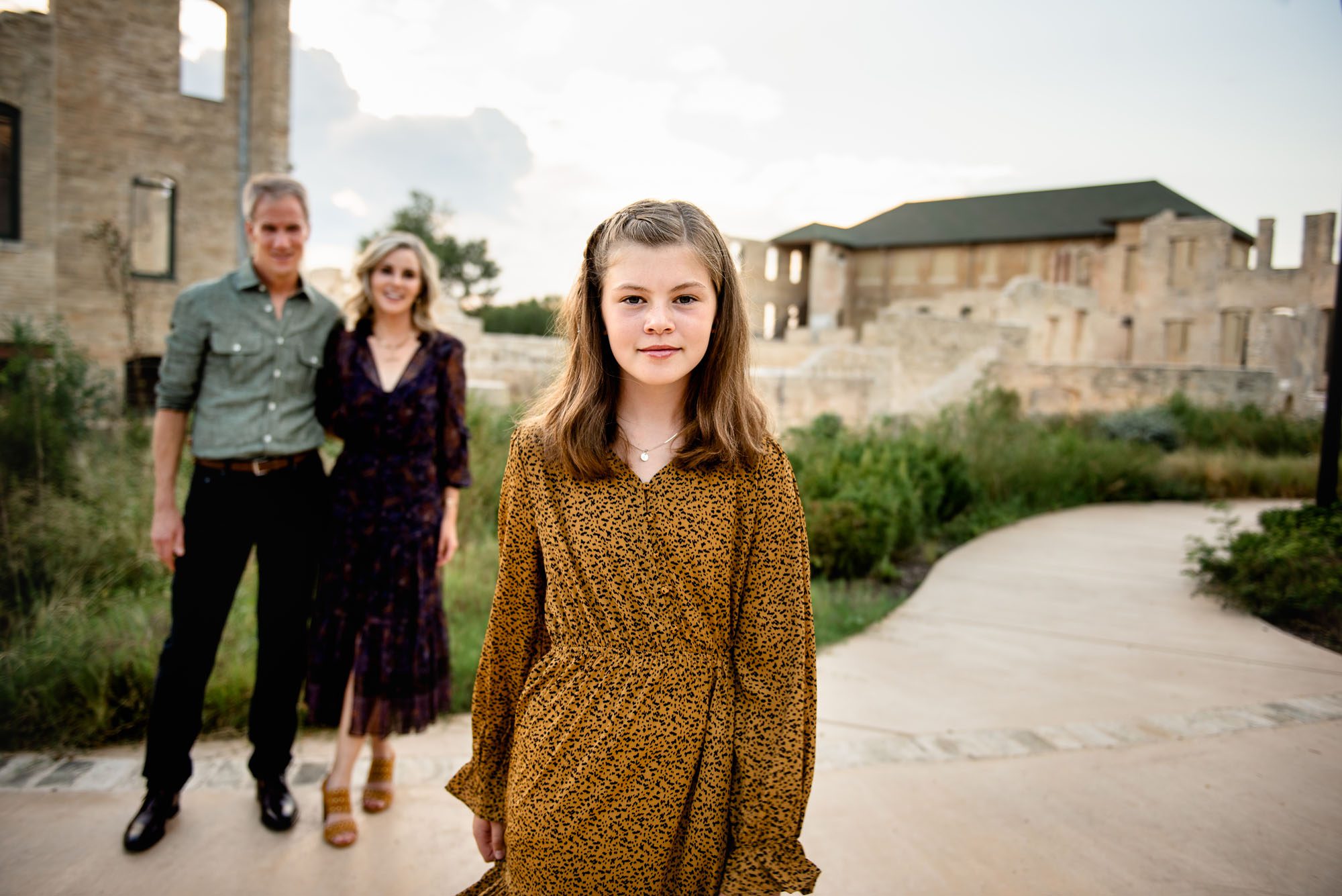 Girl standing with parents in the background, Best San Antonio Lifestyle Photographer