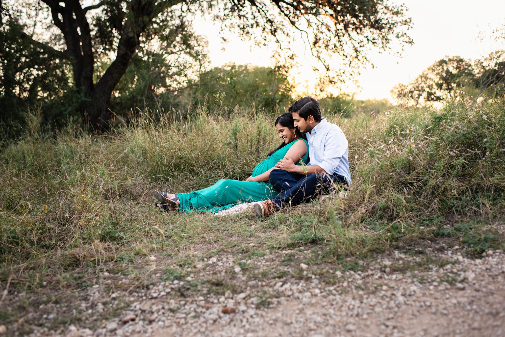 Pregnant mother and father sitting in a field, Best San Antonio Maternity Photographer