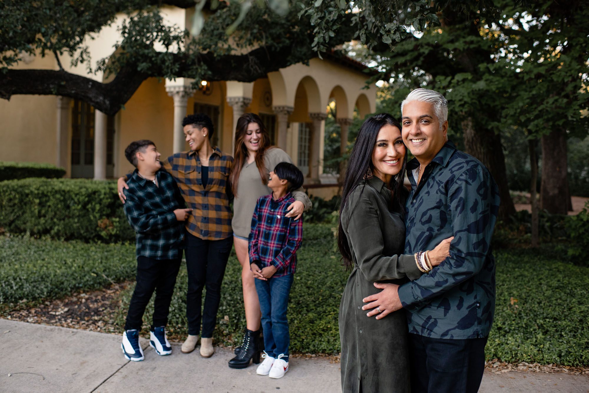 Mom and Dad hugging with kids in the background, San Antonio Family Lifestyle Photographer