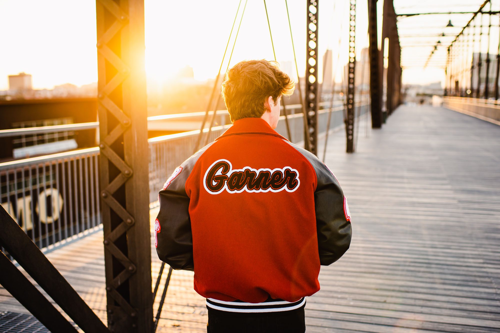 San Antonio Senior Photography, Senior boy in letter jacket on a bridge at sunset