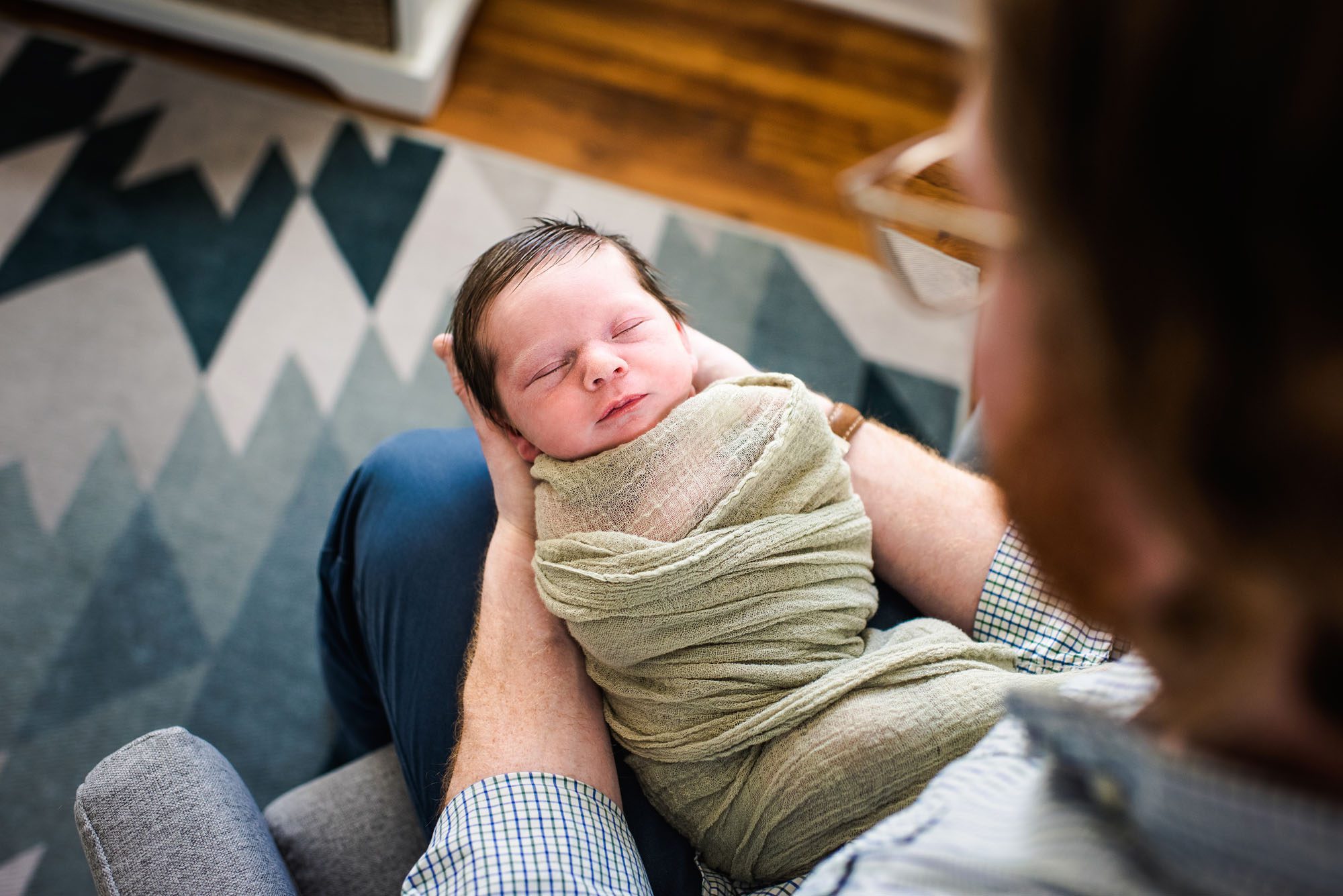 Dad holding sleeping baby in his lap, Best Newborn Photographer
