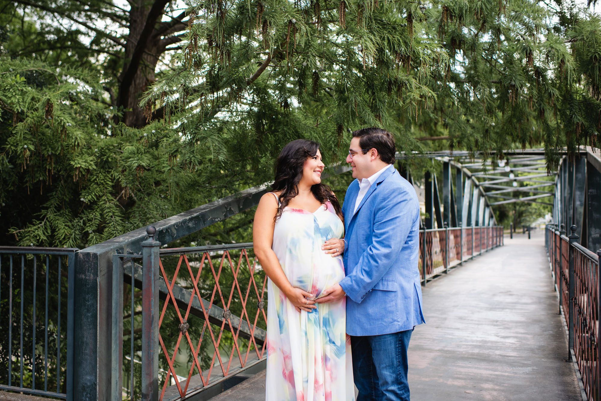 Pregnant couple smiling at each other on bridge, San Antonio Maternity Photography