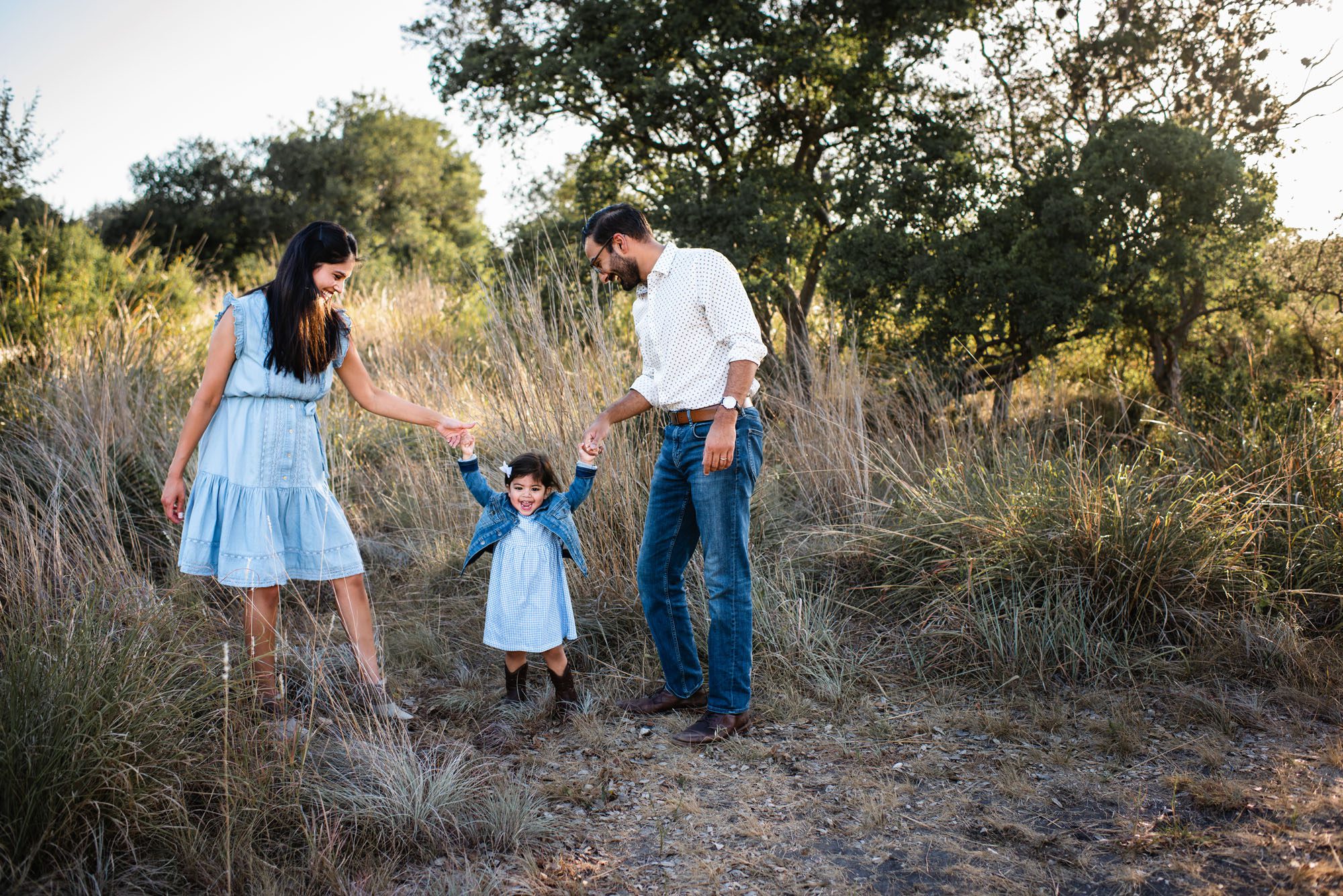 Parents walking in a field with daughter, San Antonio family photographer