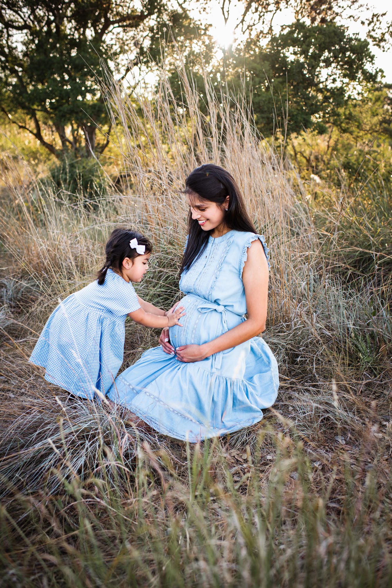 Daughter touching mother's pregnant belly in a field, San Antonio Maternity Photographer