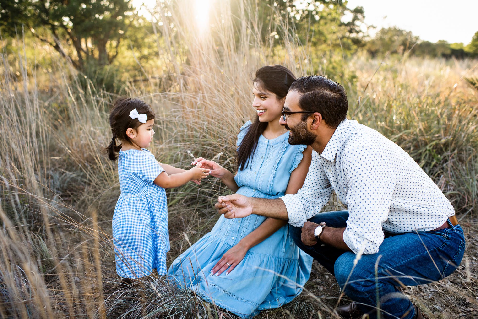 Daughter handing parents a piece of wheat in a field, San Antonio Maternity Photographer