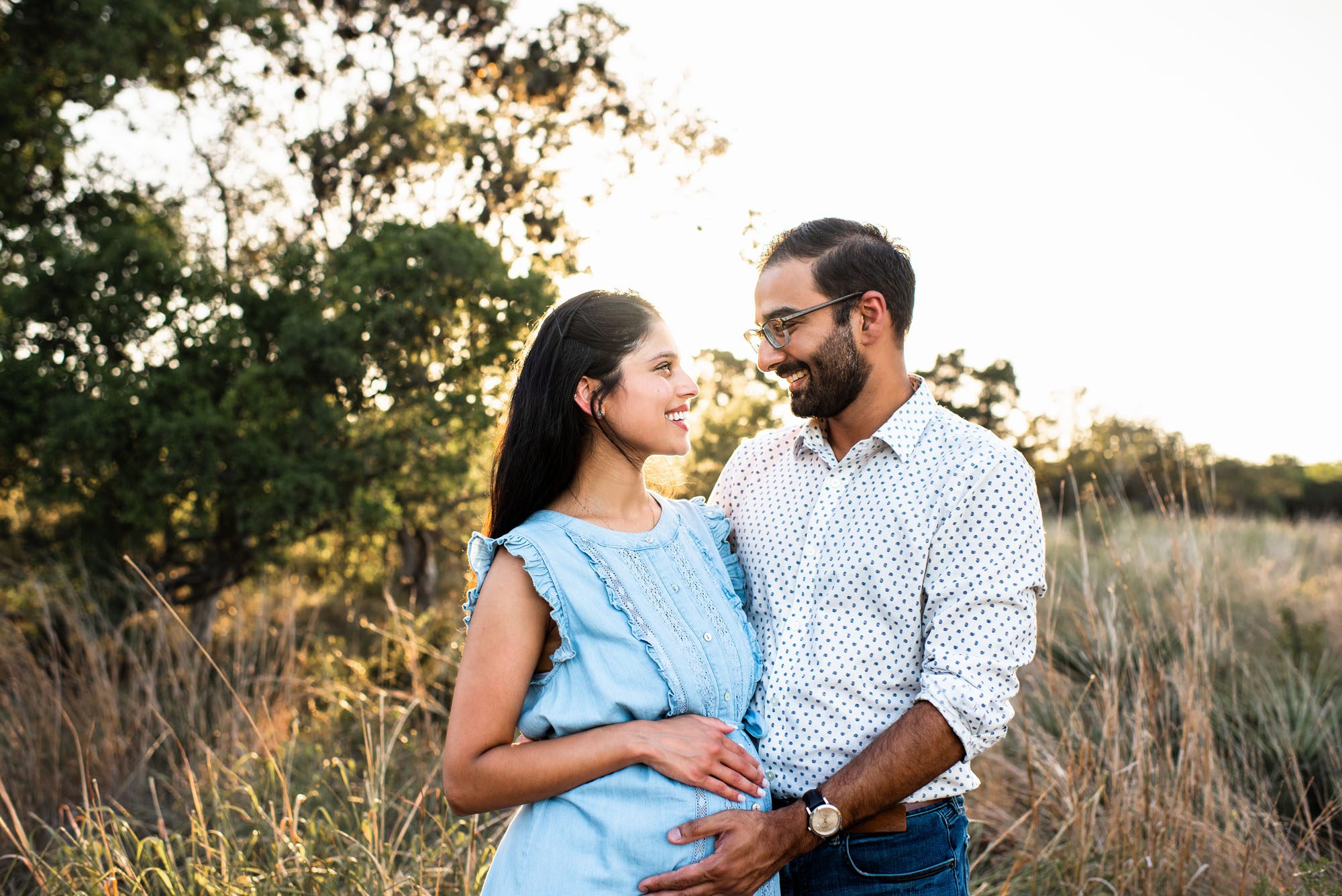 Expectant couple smiling at each other at sunset, San Antonio lifestyle maternity photographer