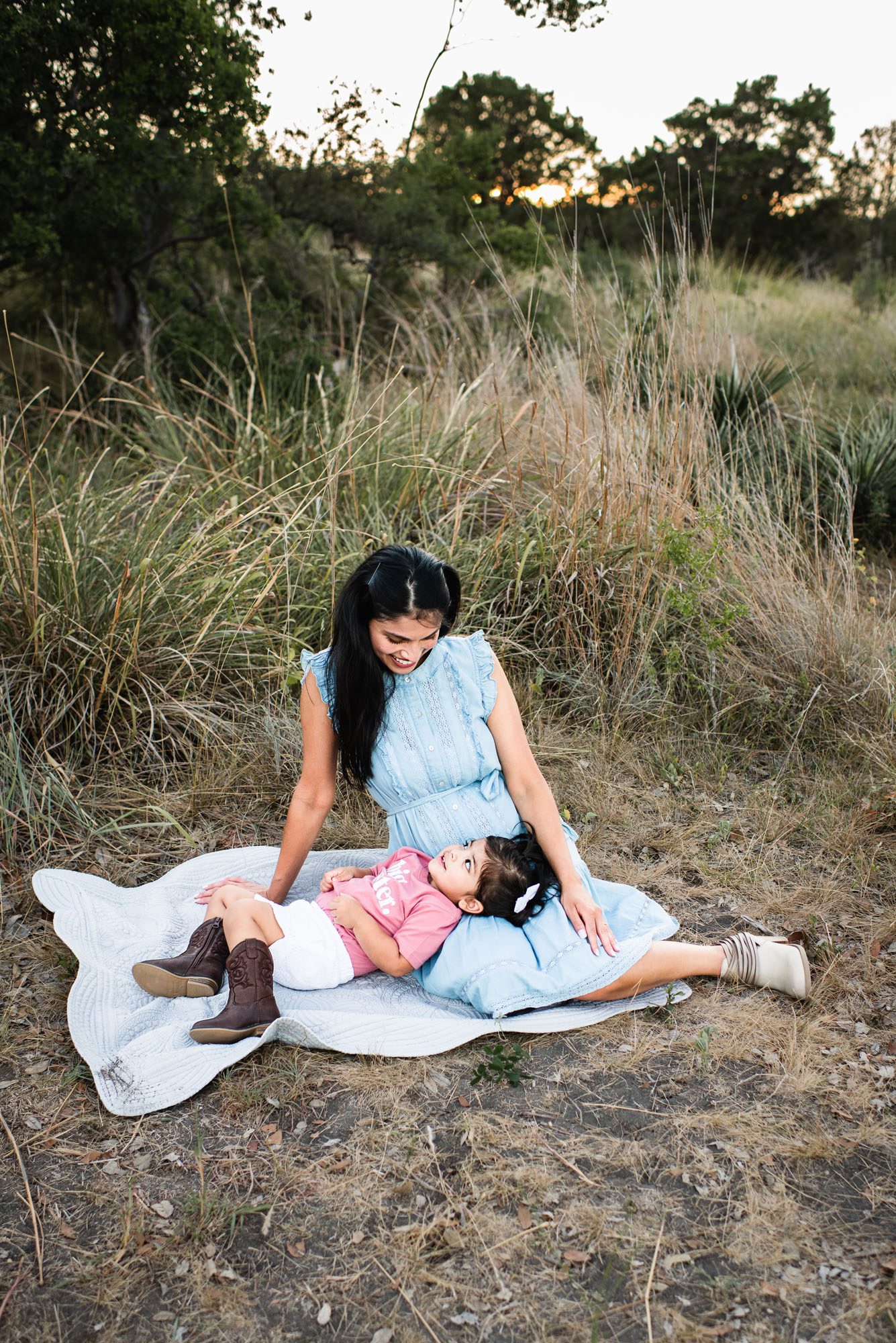 Daughter laying in mother's lap and smiling, Best San Antonio Maternity photographer