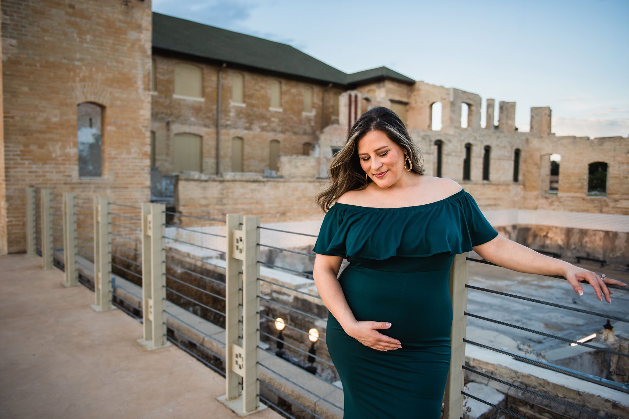 Pregnant mom in green dress looking down at belly bump, San Antonio Maternity Photography