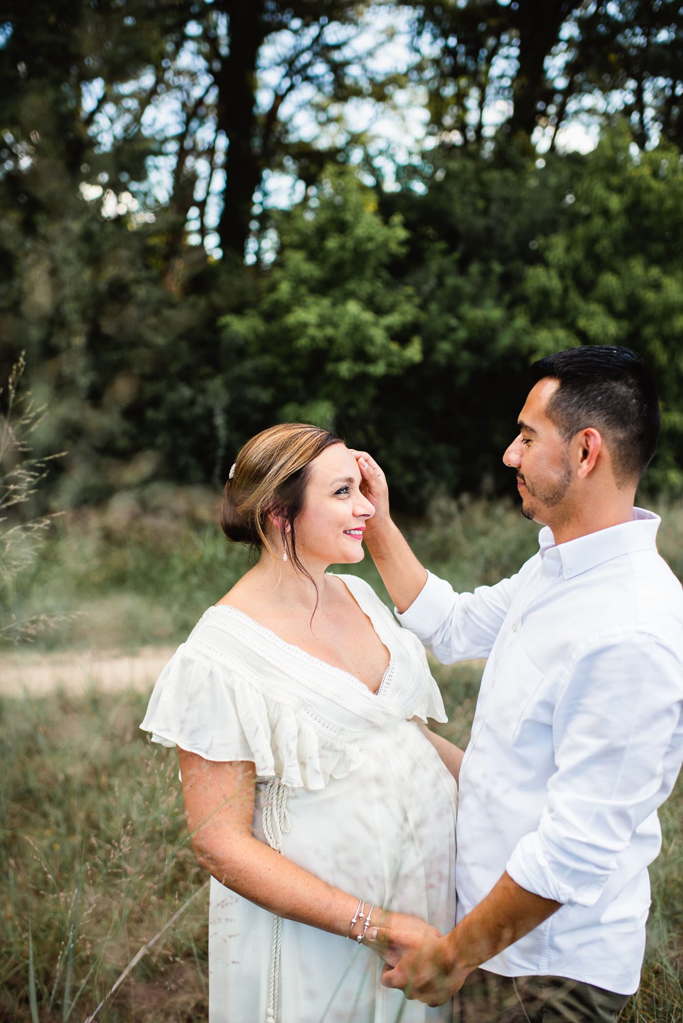 Pregnant mom smiling at husband in a field, San Antonio maternity photographer