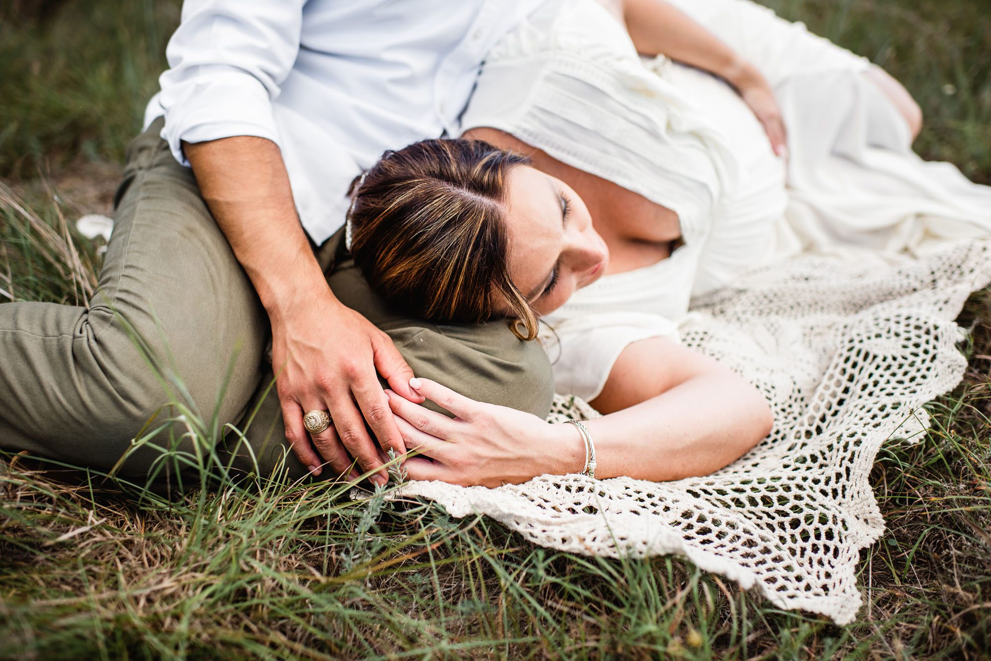 Pregnant woman laying on husband's lap in a field, San Antonio maternity photographer