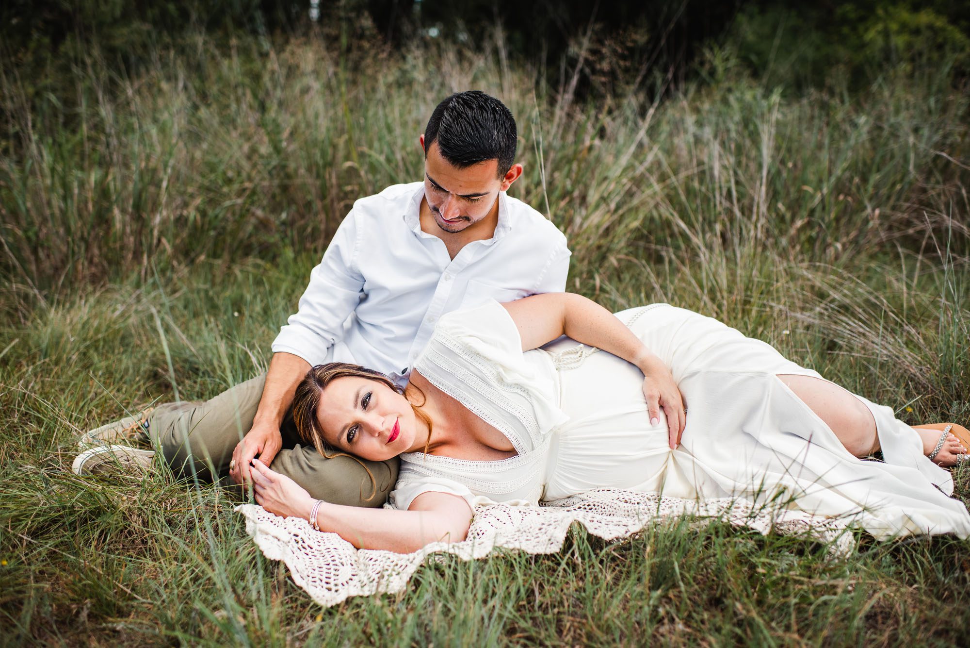 Pregnant woman laying on husband's lap in a field, San Antonio maternity photographer