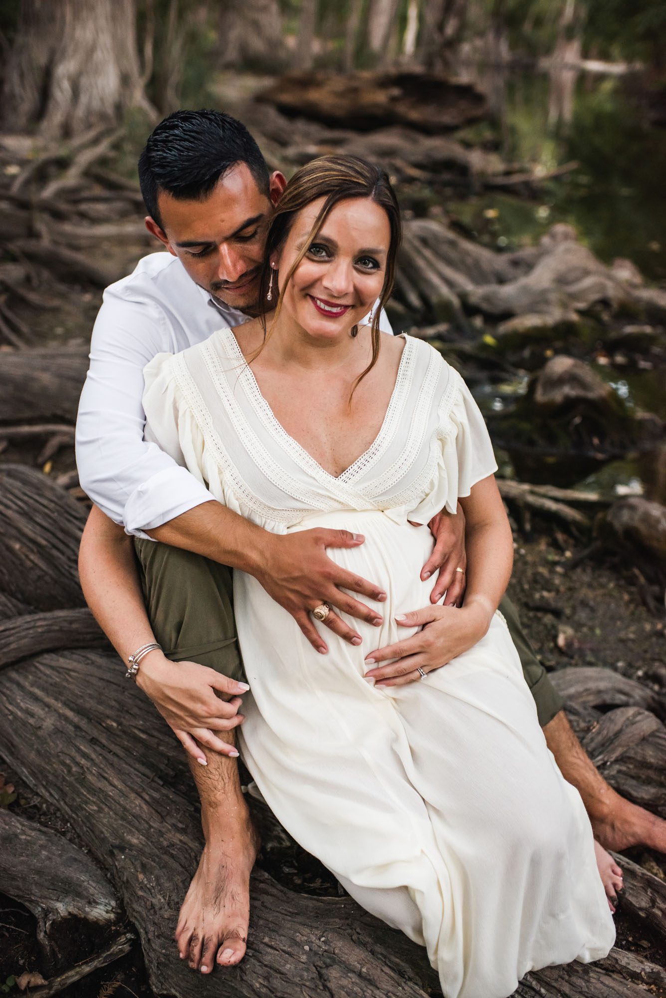 San Antonio Maternity Photographer, pregnant couple sitting together in creek