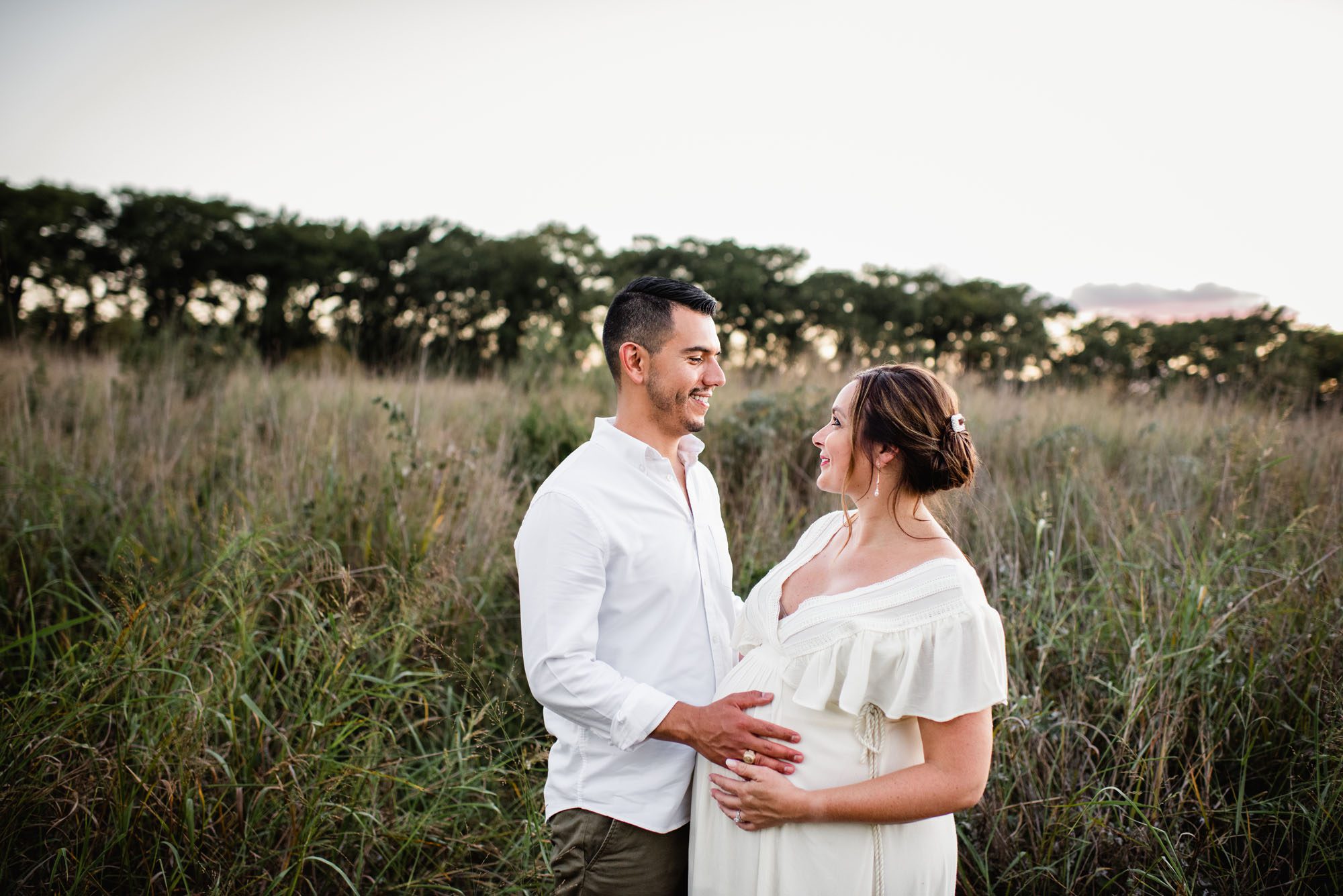 San Antonio Maternity Photographer, pregnant couple smiling at each other in field