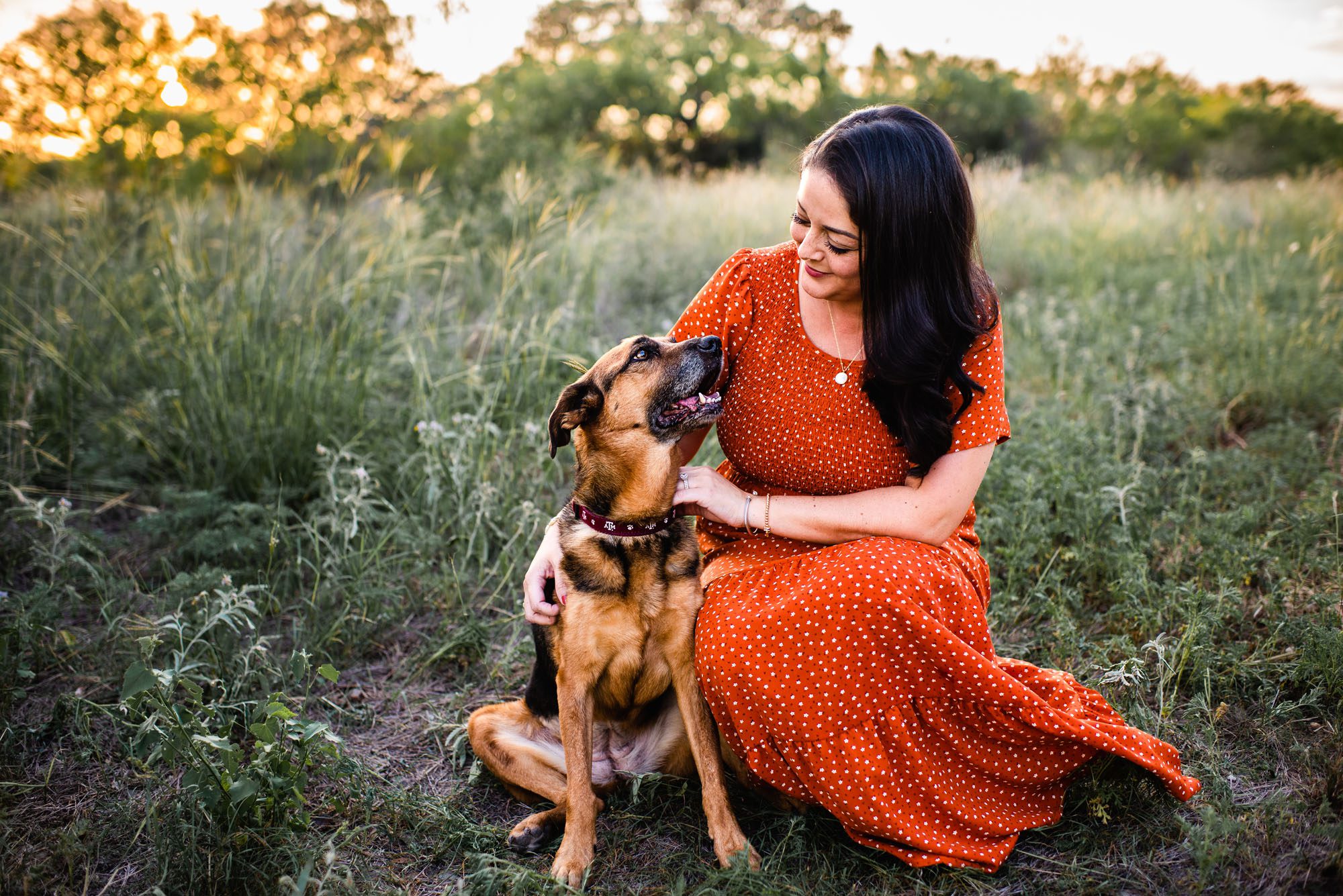 Woman smiling at her dog in a field at sunset, San Antonio family lifestyle photographer