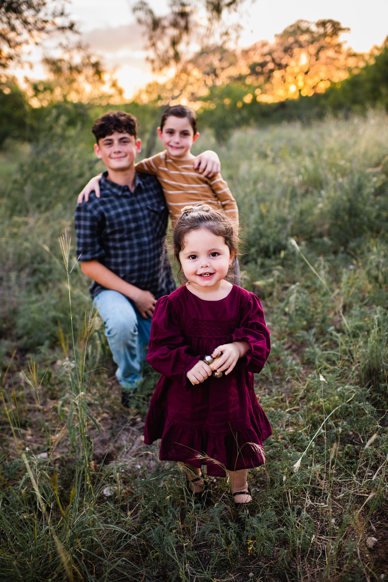 little girl smiling with brothers in the background , San Antonio family photographer