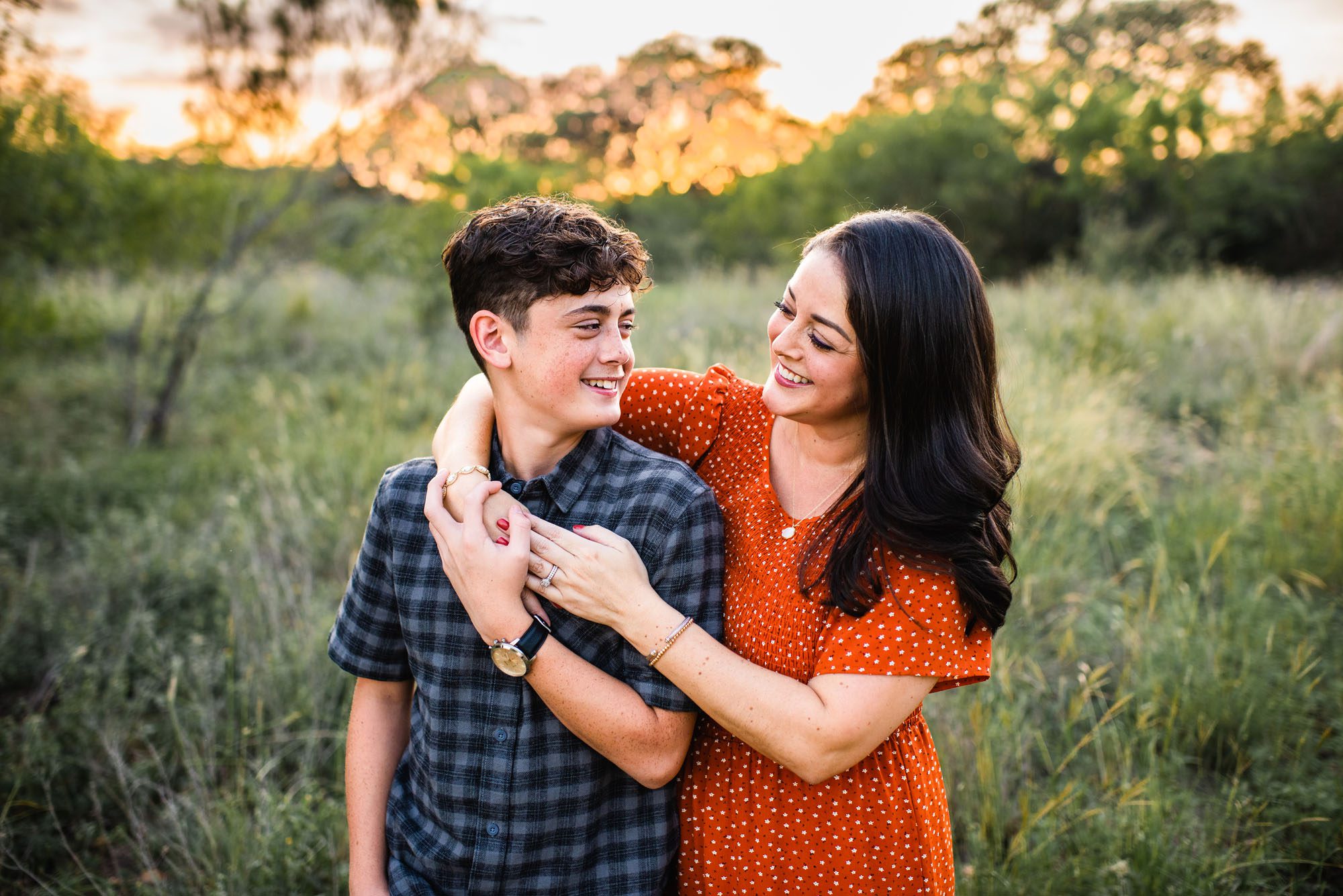 Mother smiling at son in a green field, family photographer in San Antonio