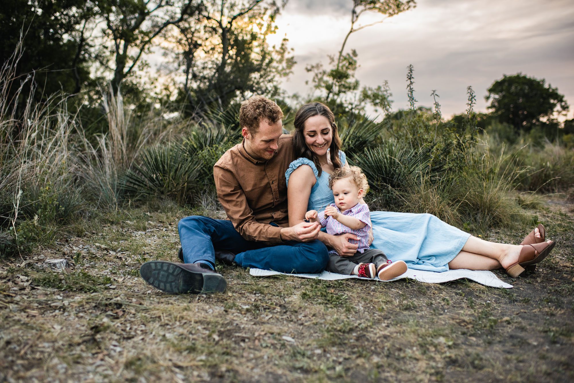 Family with little boy sitting on blanket in a field, San Antonio Lifestyle Photographer