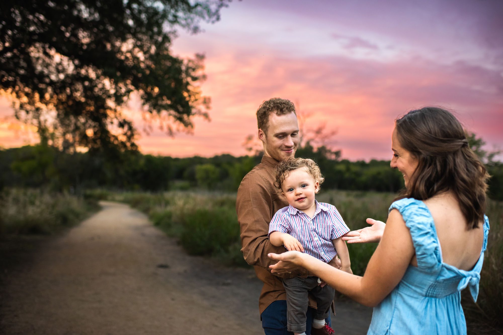 Parents playing with baby boy by walking path with colorful sunset, San Antonio Family Photographer
