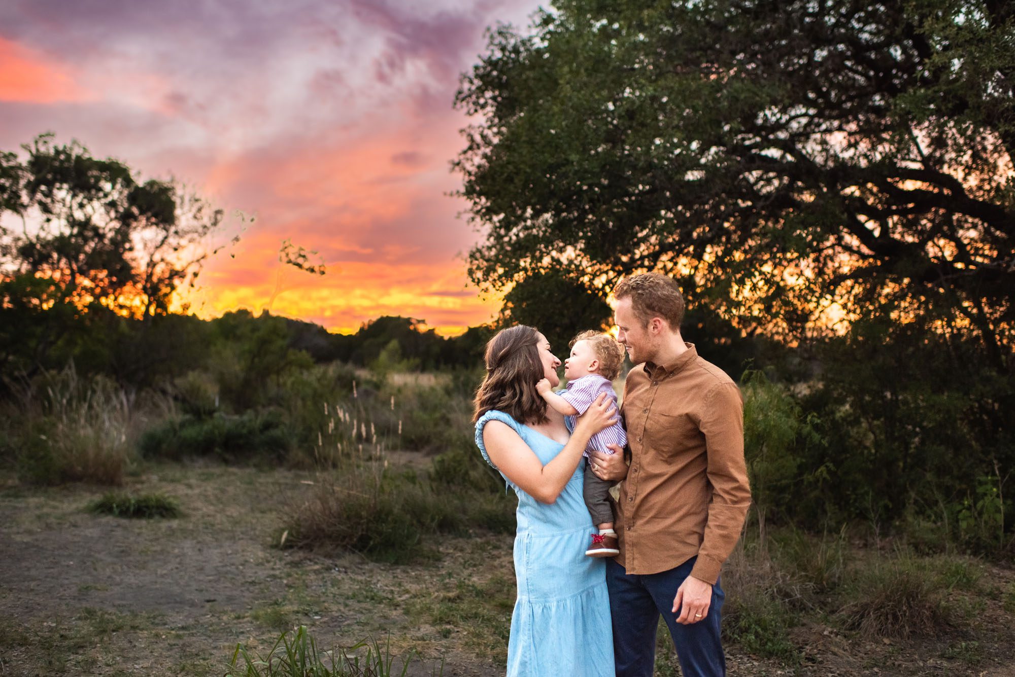 Parents holding baby boy in field with colorful sunset, San Antonio Family Photographer