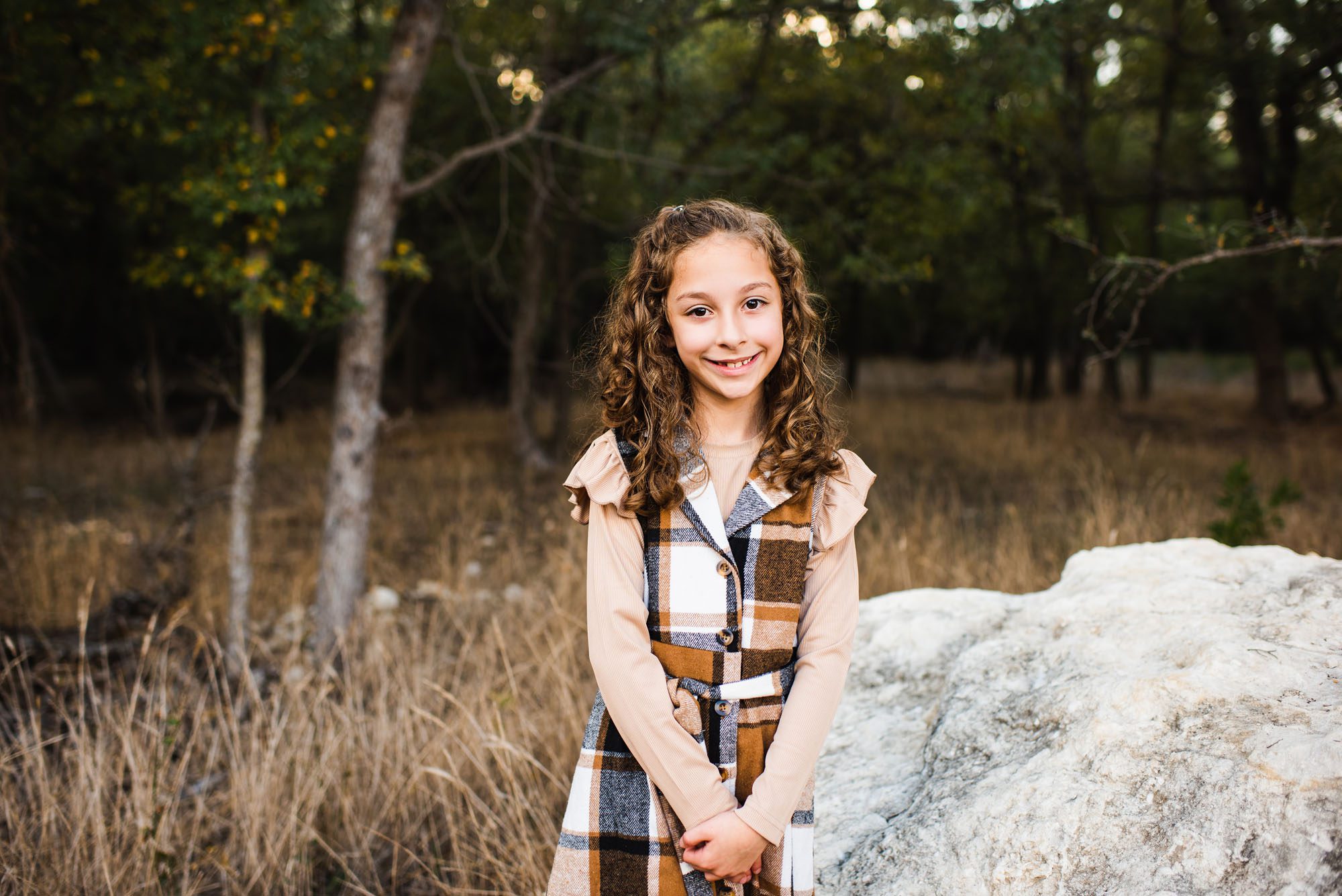 Young girls smiling near rock in woods, San Antonio Family Lifestyle Photographer